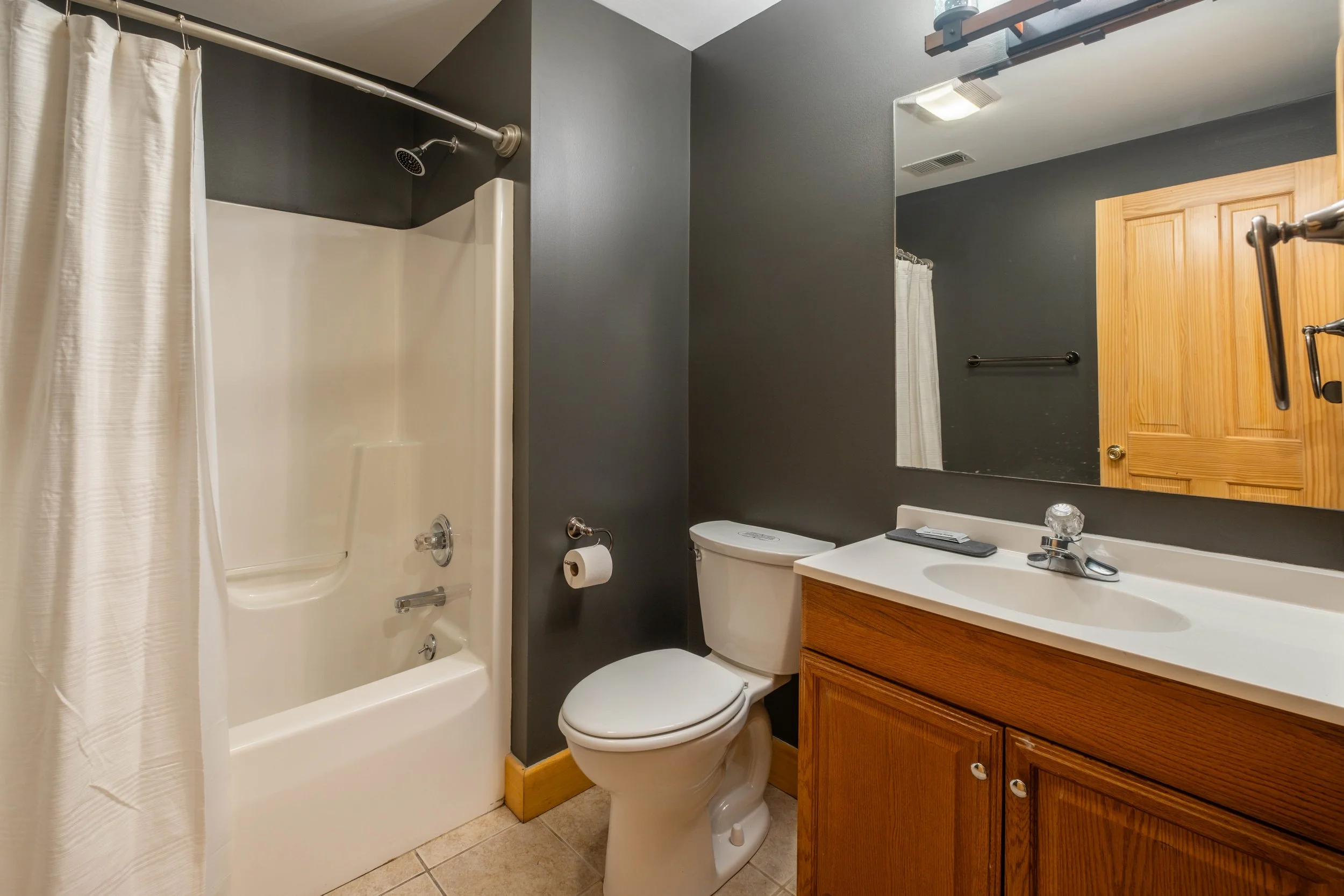 Bathroom with a shower, toilet, and wooden vanity with sink.