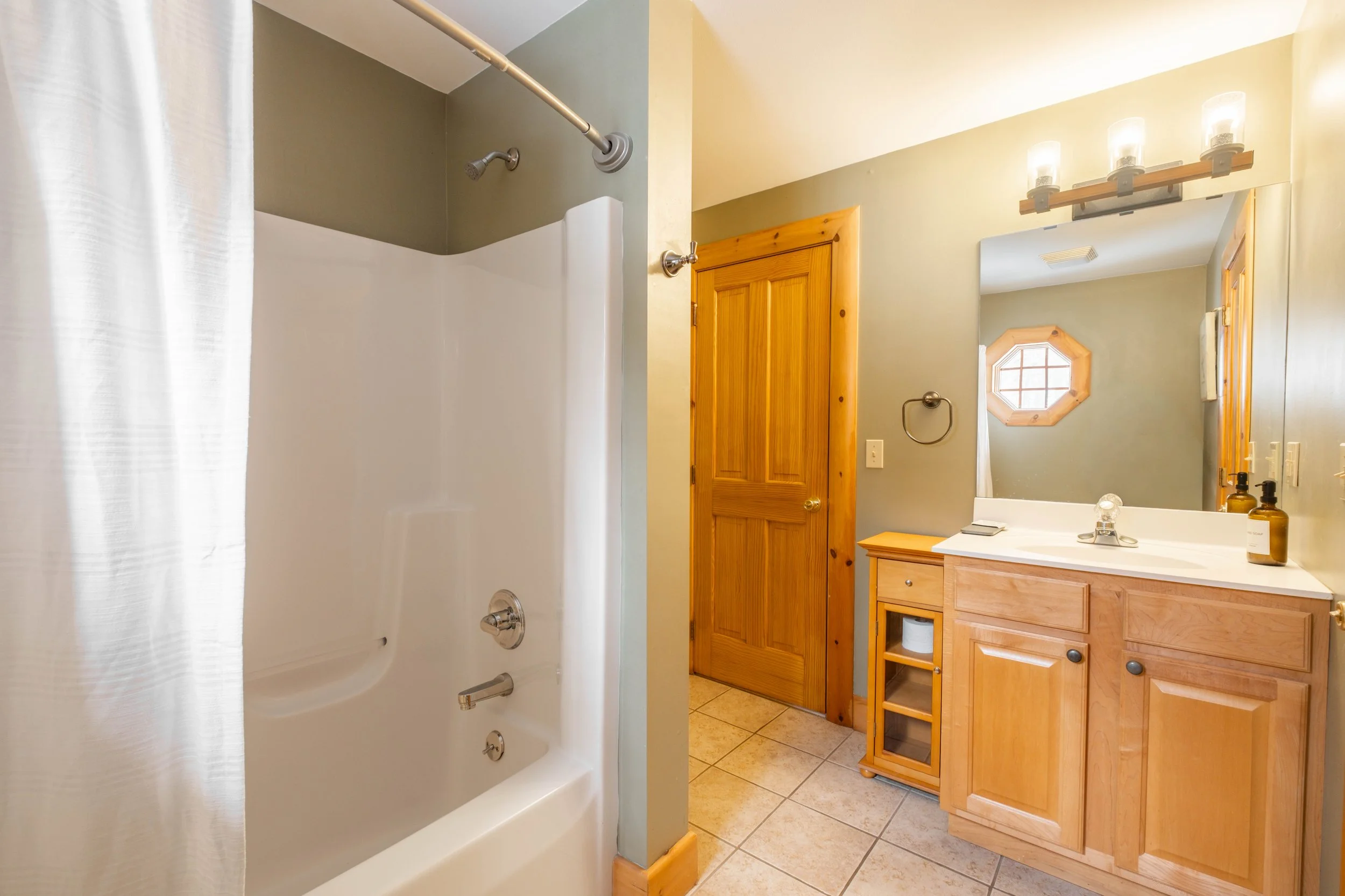 Bathroom with a shower, wooden cabinets, and a small window.
