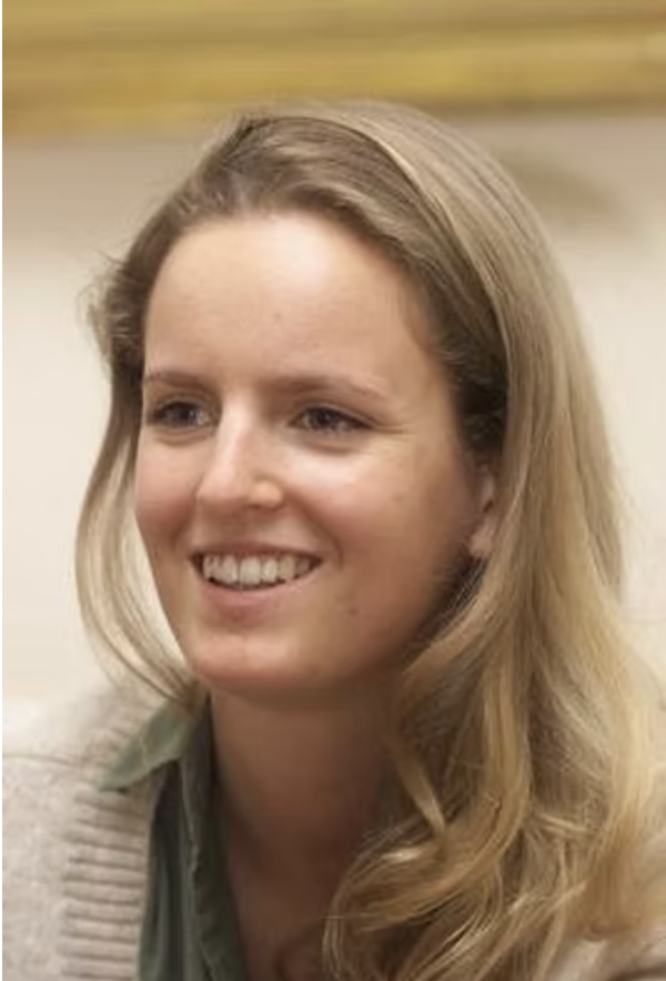 Lächelnde junge Frau mit langem, lockigem, blondem Haar, im Hintergrund unscharf.