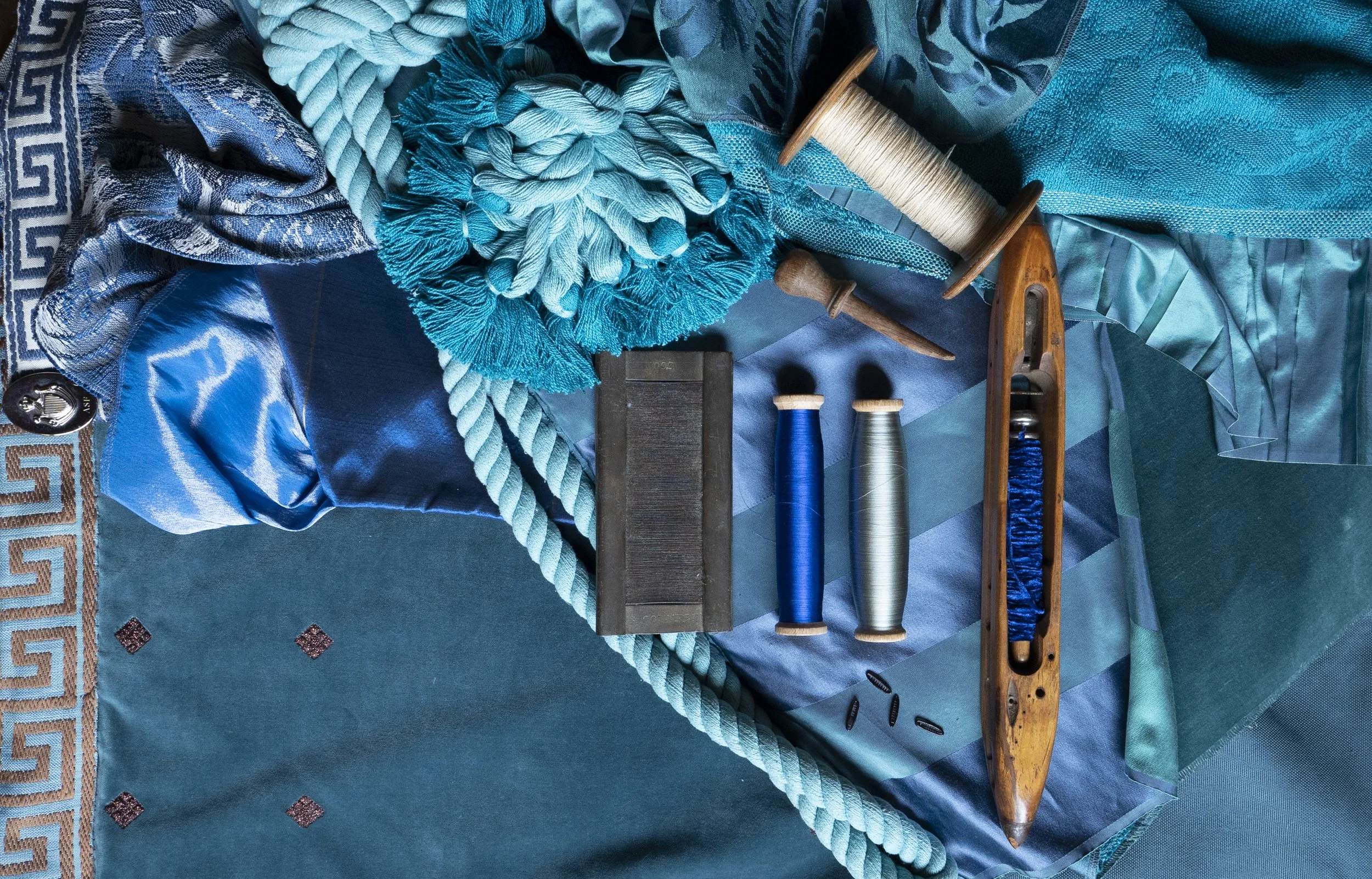 Collection of blue fabrics, thread spools, and sewing tools.