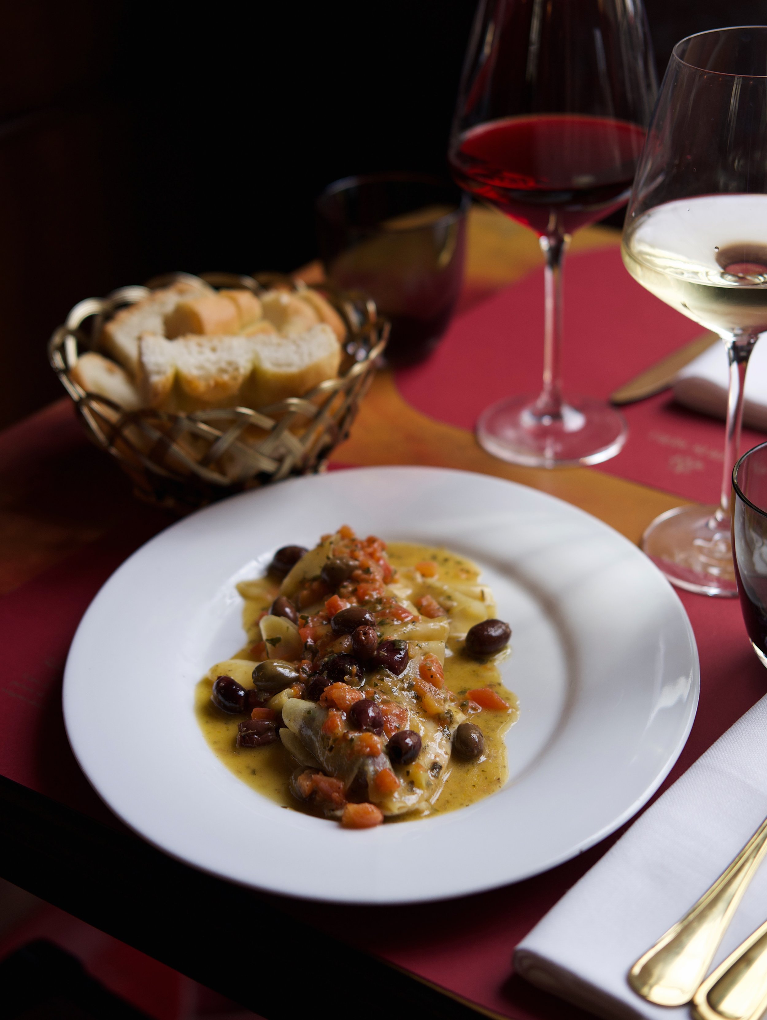 Plate of pasta with sauce, black beans, and vegetables on a dining table.