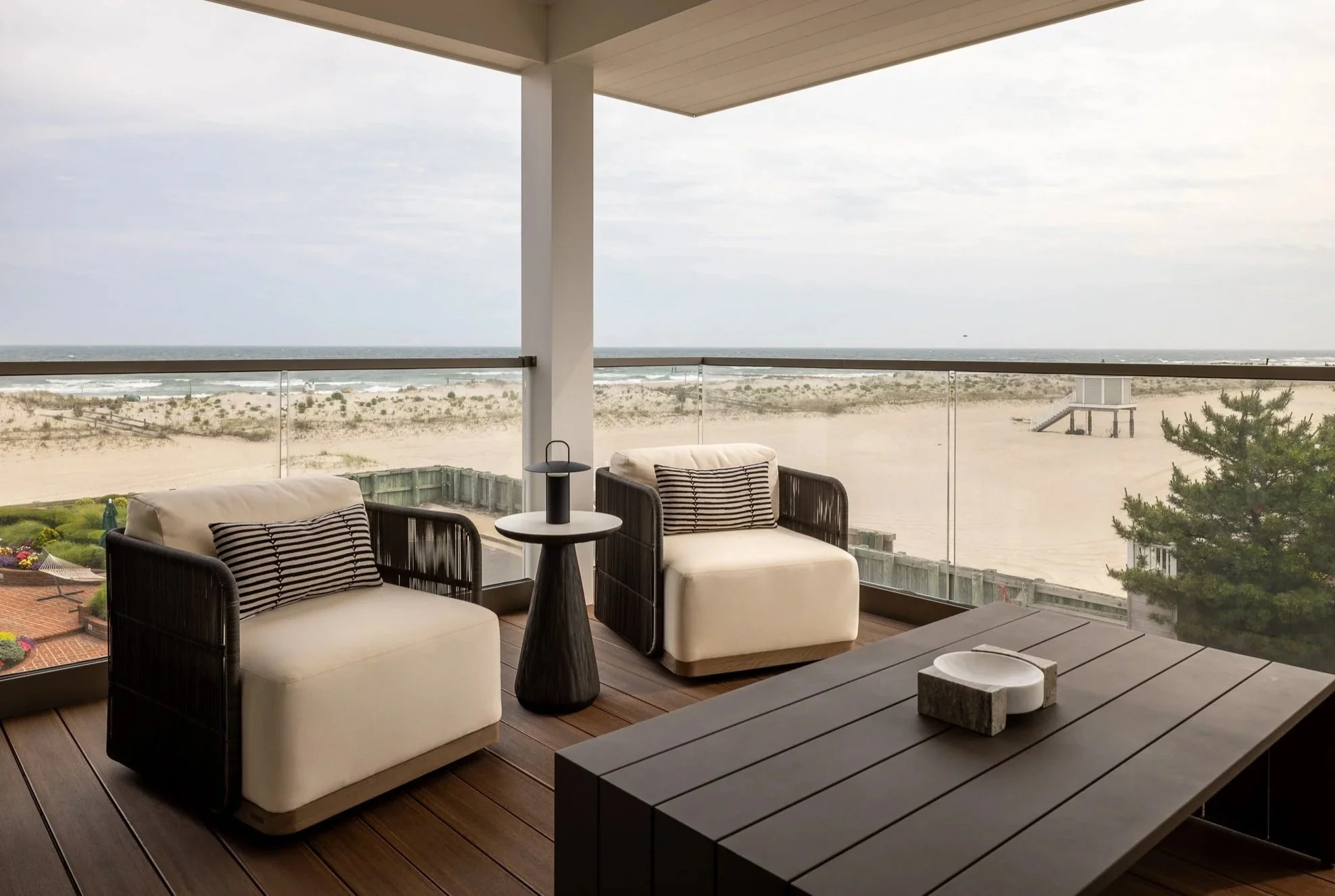 Stunning glass walled deck for a New Jersey beach house with light chairs and a dark table