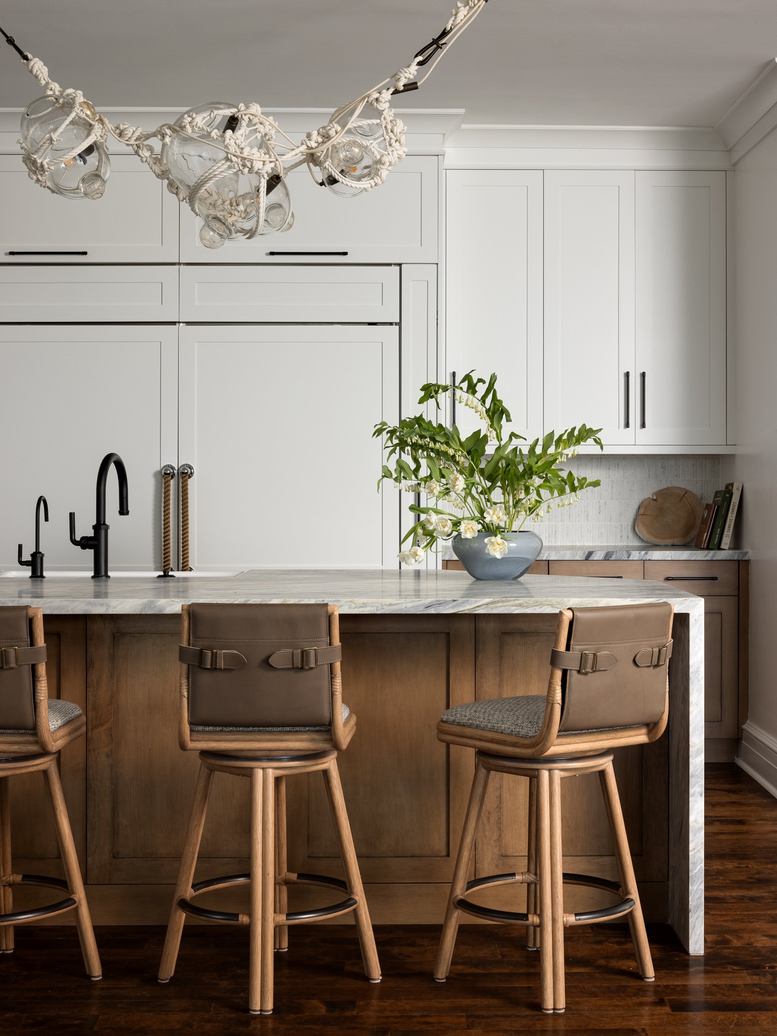 light kitchen with waterfall marble island and a nautical chandelier