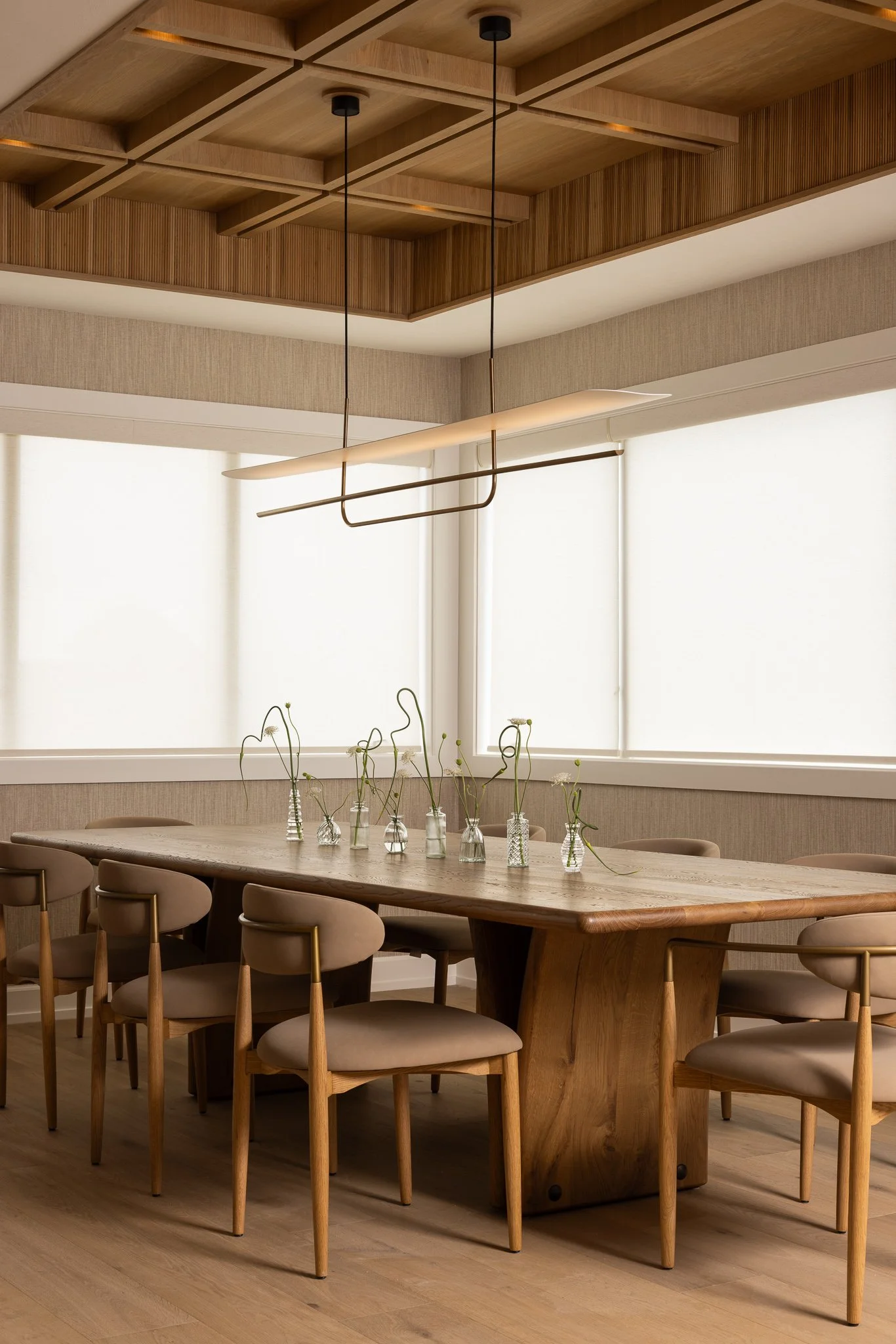 light millwork dining table with a stunning wooden ceiling and soft oatmeal chairs