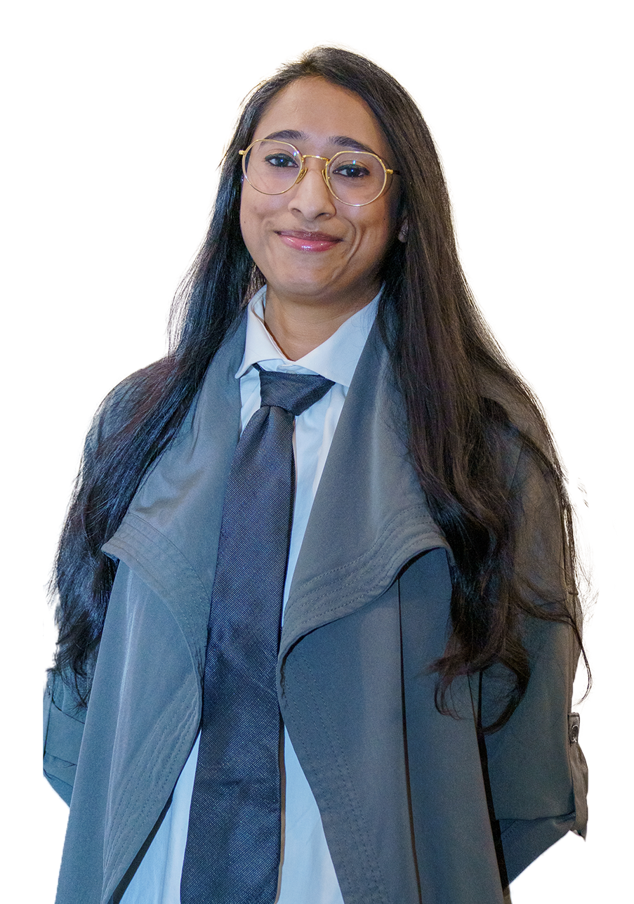 A smiling woman with long dark hair, glasses, and a professional outfit, standing against a light-colored background.