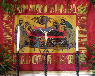 Religious iconography depicting the Virgin Mary and Jesus Christ surrounded by saints, with candles on a black wrought iron candle holder in front.