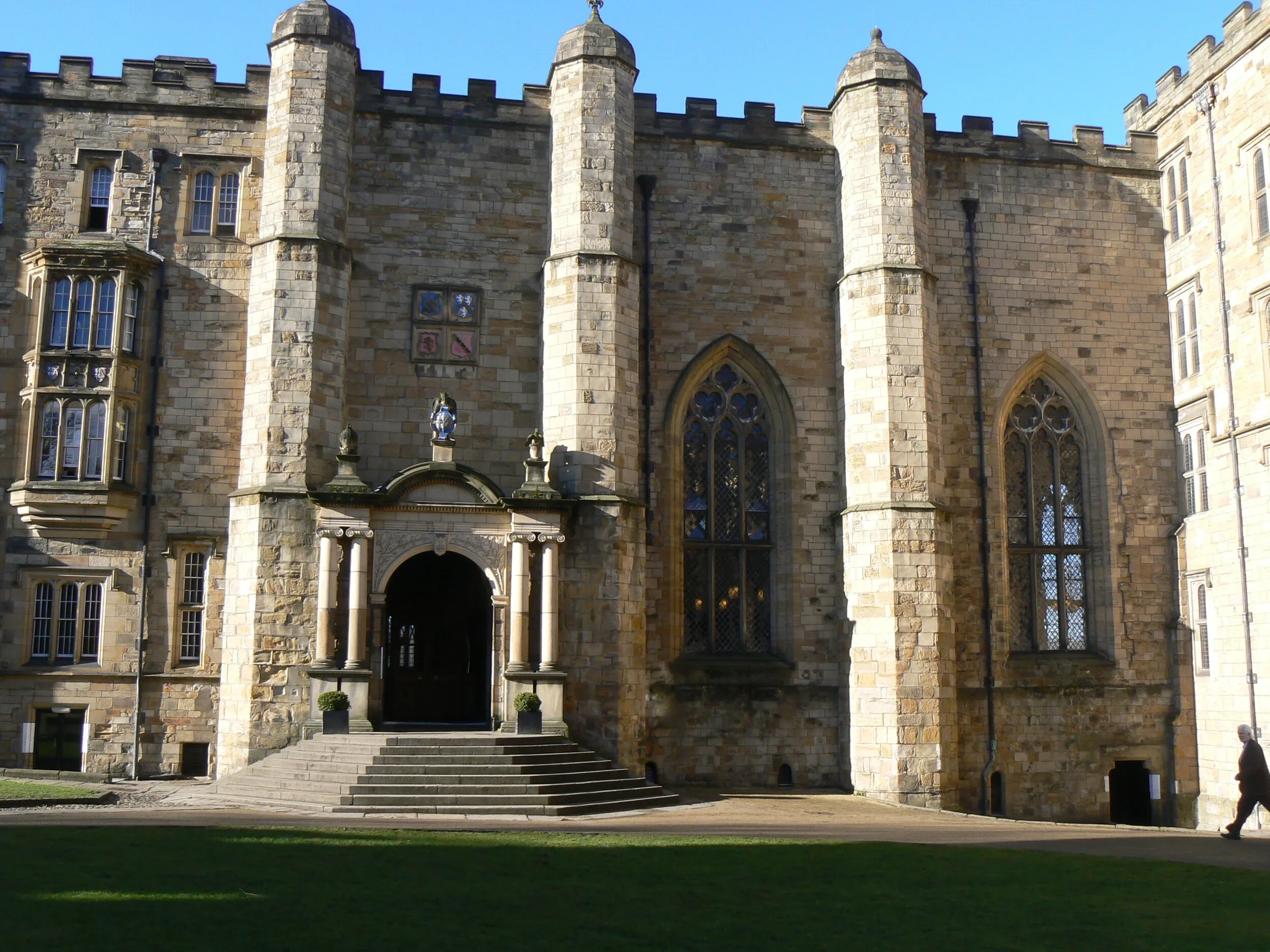 A stone clock tower with a black clock face and Roman numerals against a blue sky.