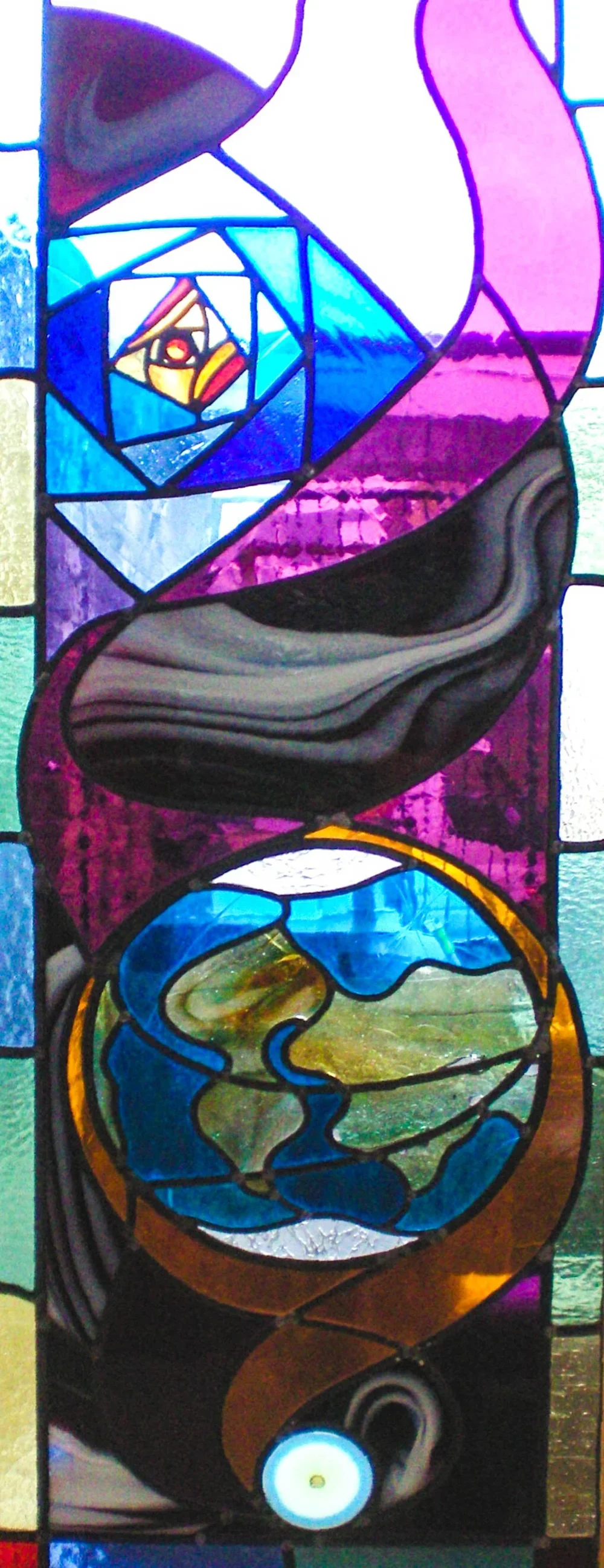 Abstract stained glass window featuring a spiral pattern with Earth in the center and various colors including blue, green, purple, and black.
