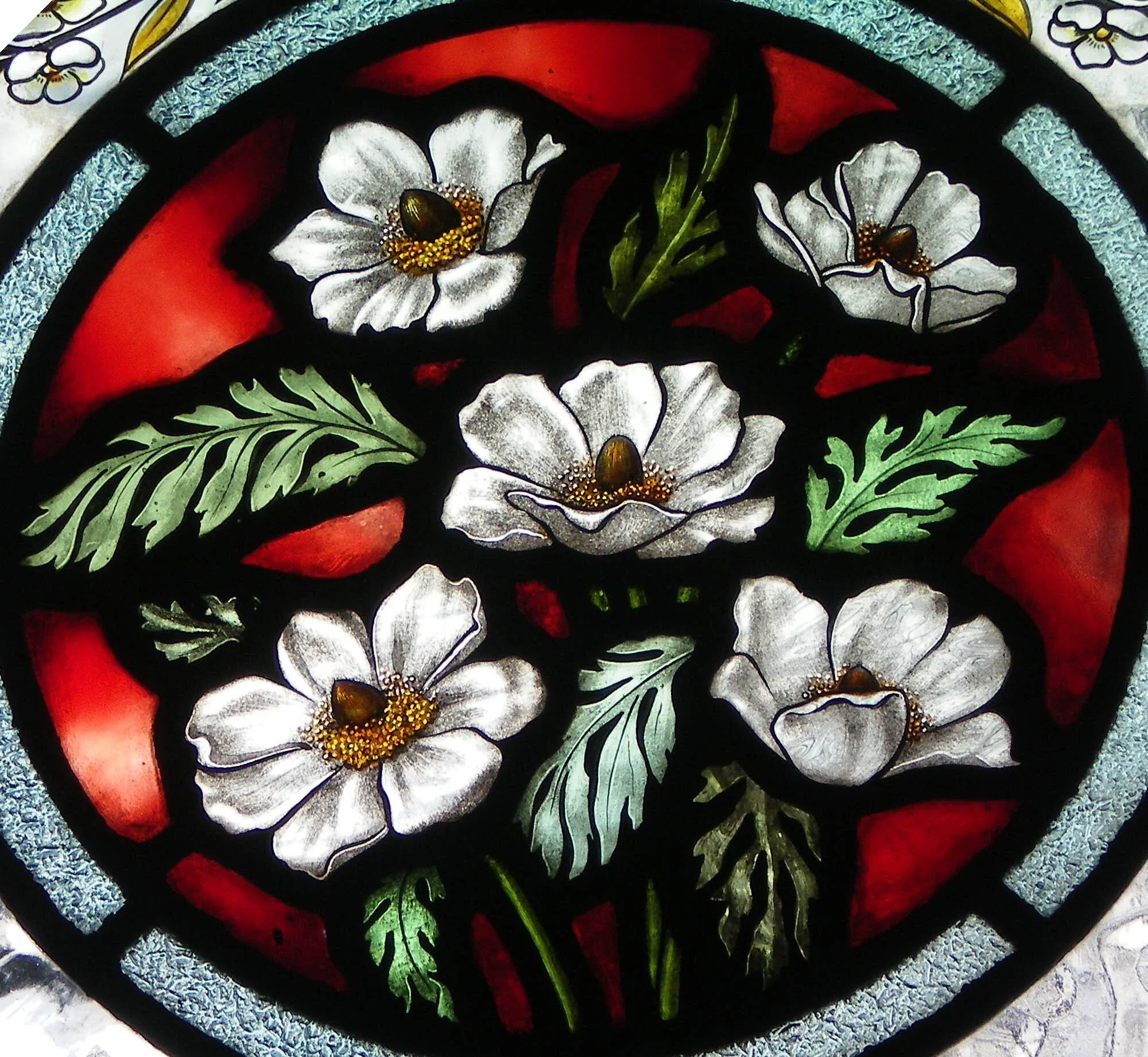 Colorful stained glass artwork featuring white flowers with black outlines, green leaves, red accents, and a silver textured background.