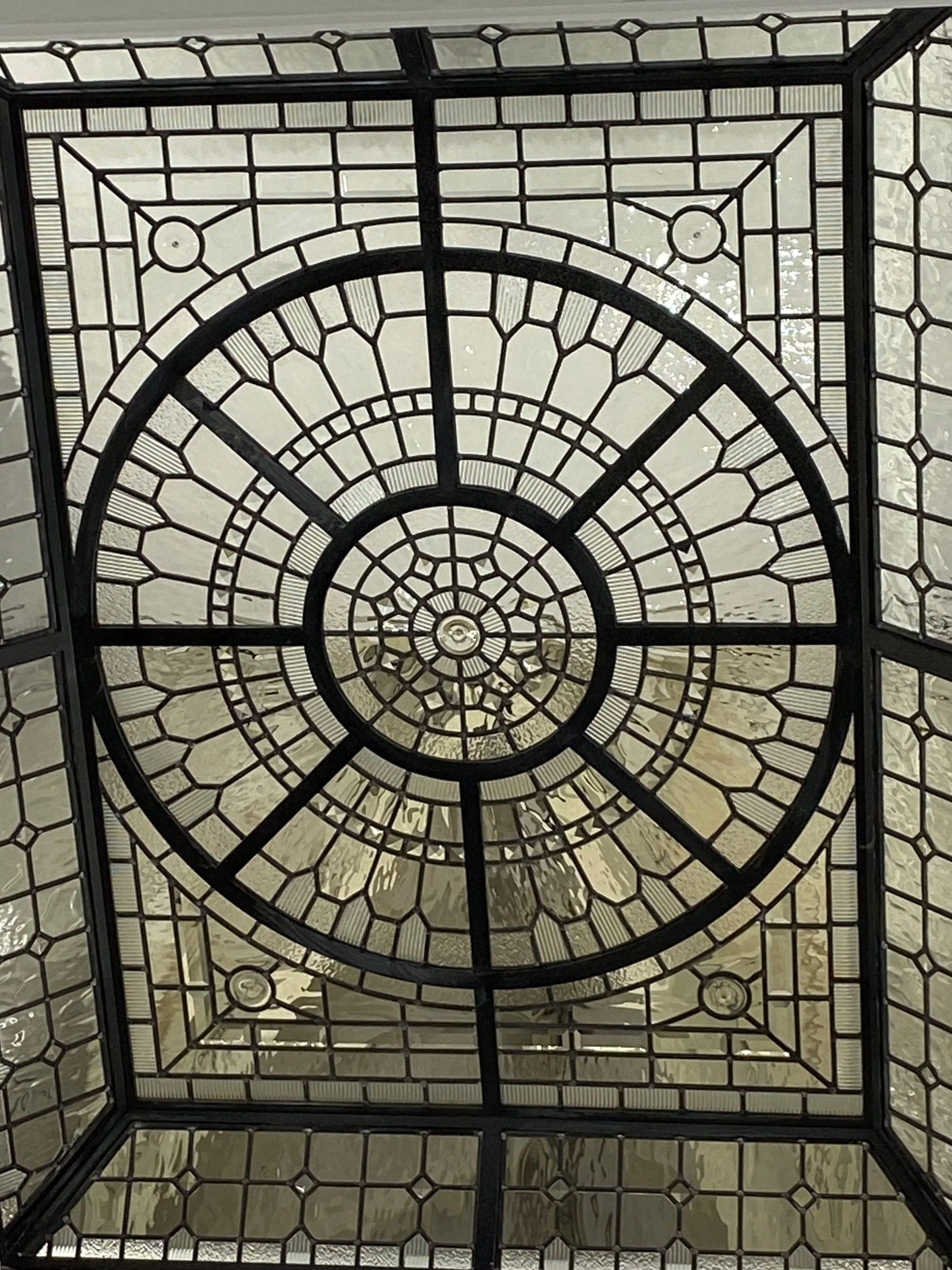 Looking up through an ornate glass and metal ceiling with a spiral pattern.