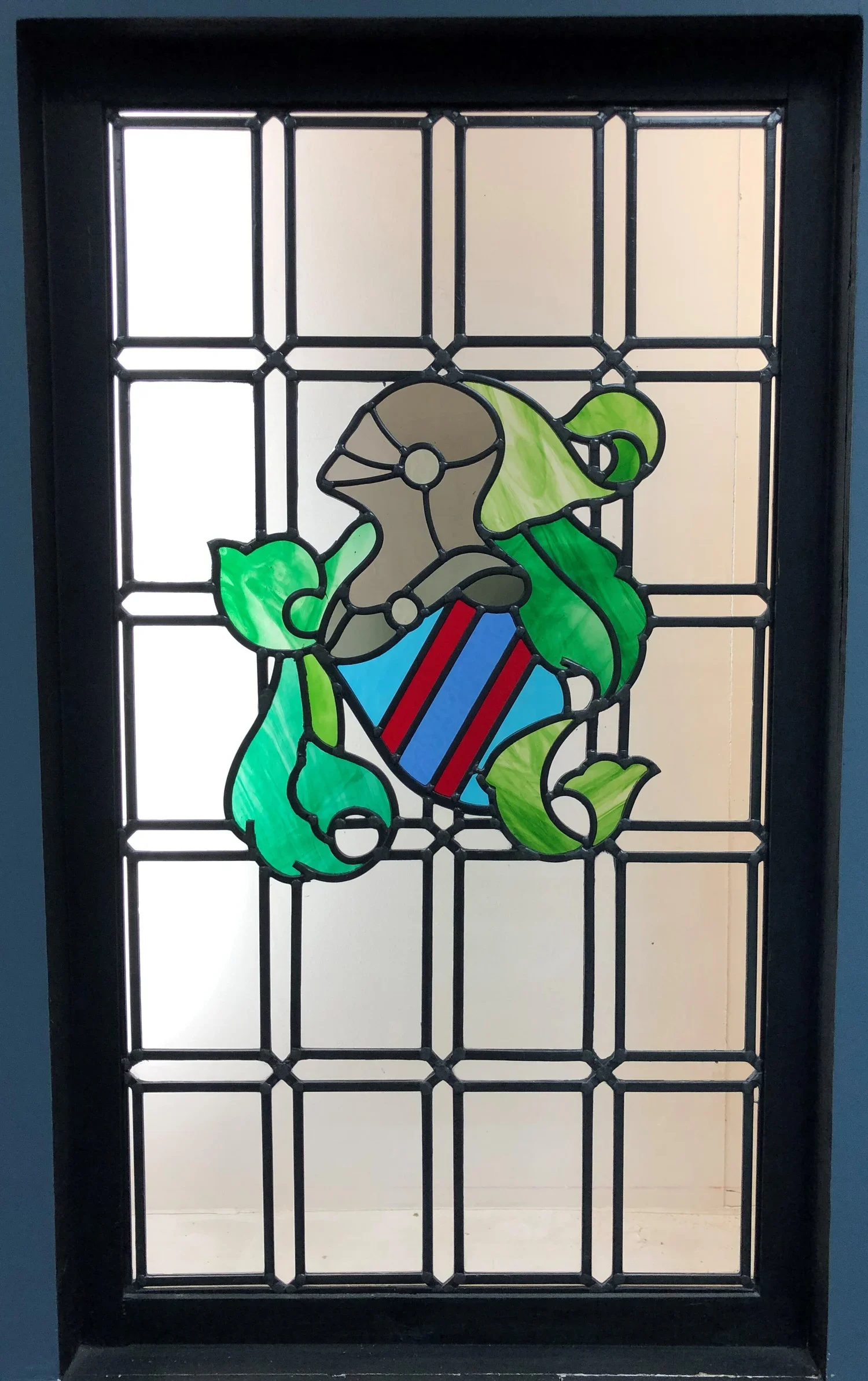 Decorative stained glass window featuring a puppy with a gift box, surrounded by a grid of black metal frame.