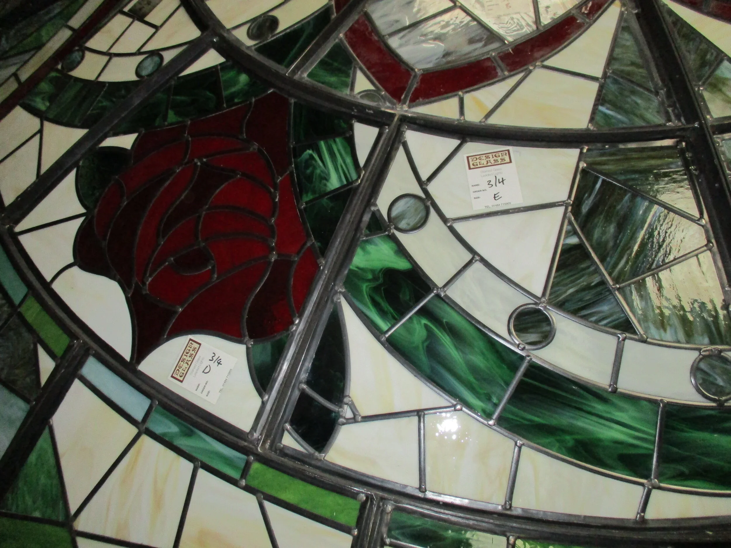 Colorful stained glass window with geometric patterns composed of various shapes and colors, including red, green, cream, and blue sections.