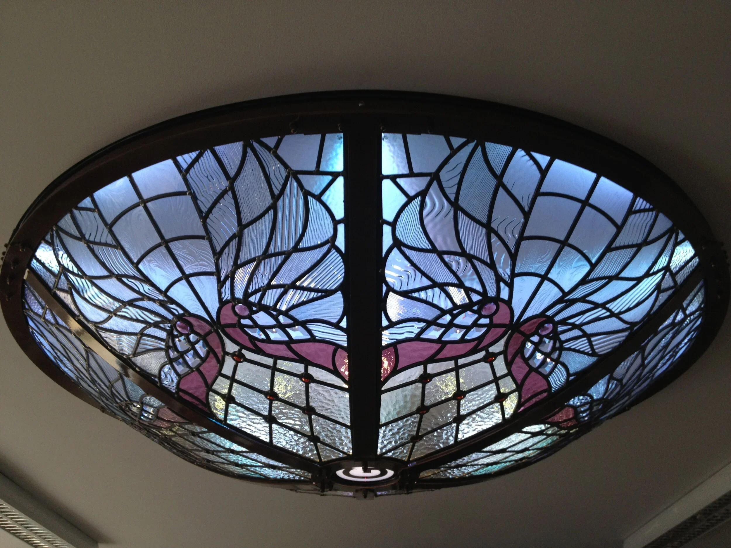 Stained glass ceiling light fixture with a butterfly design, seen from below.
