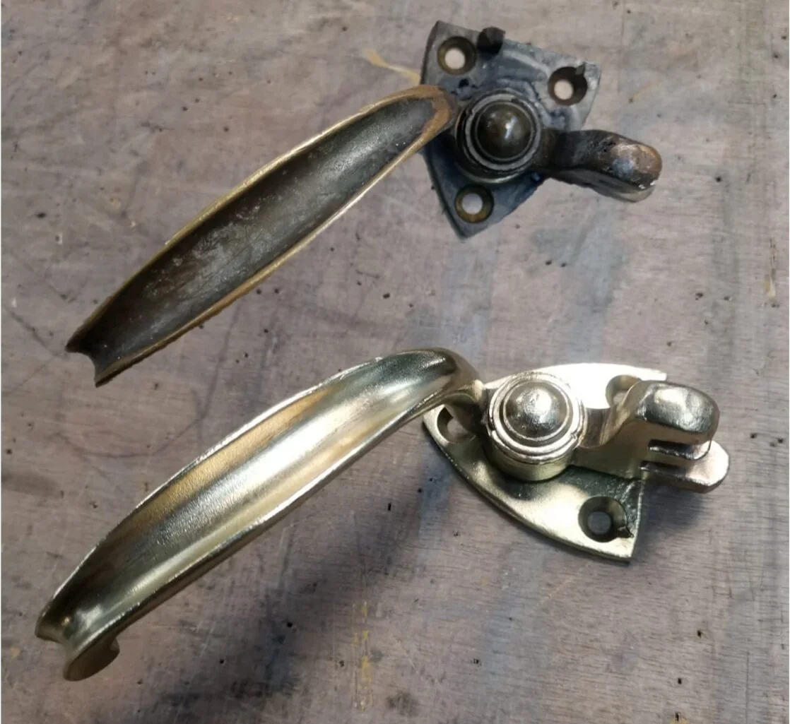 Two door handles with visible ball joints, one old and rusty, the other new and shiny, placed on a wooden surface.