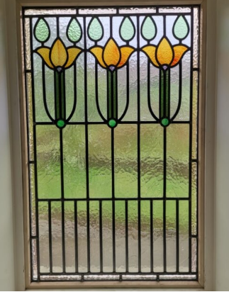 Decorative glass door with stained glass floral pattern featuring yellow and green flowers and black outlines.