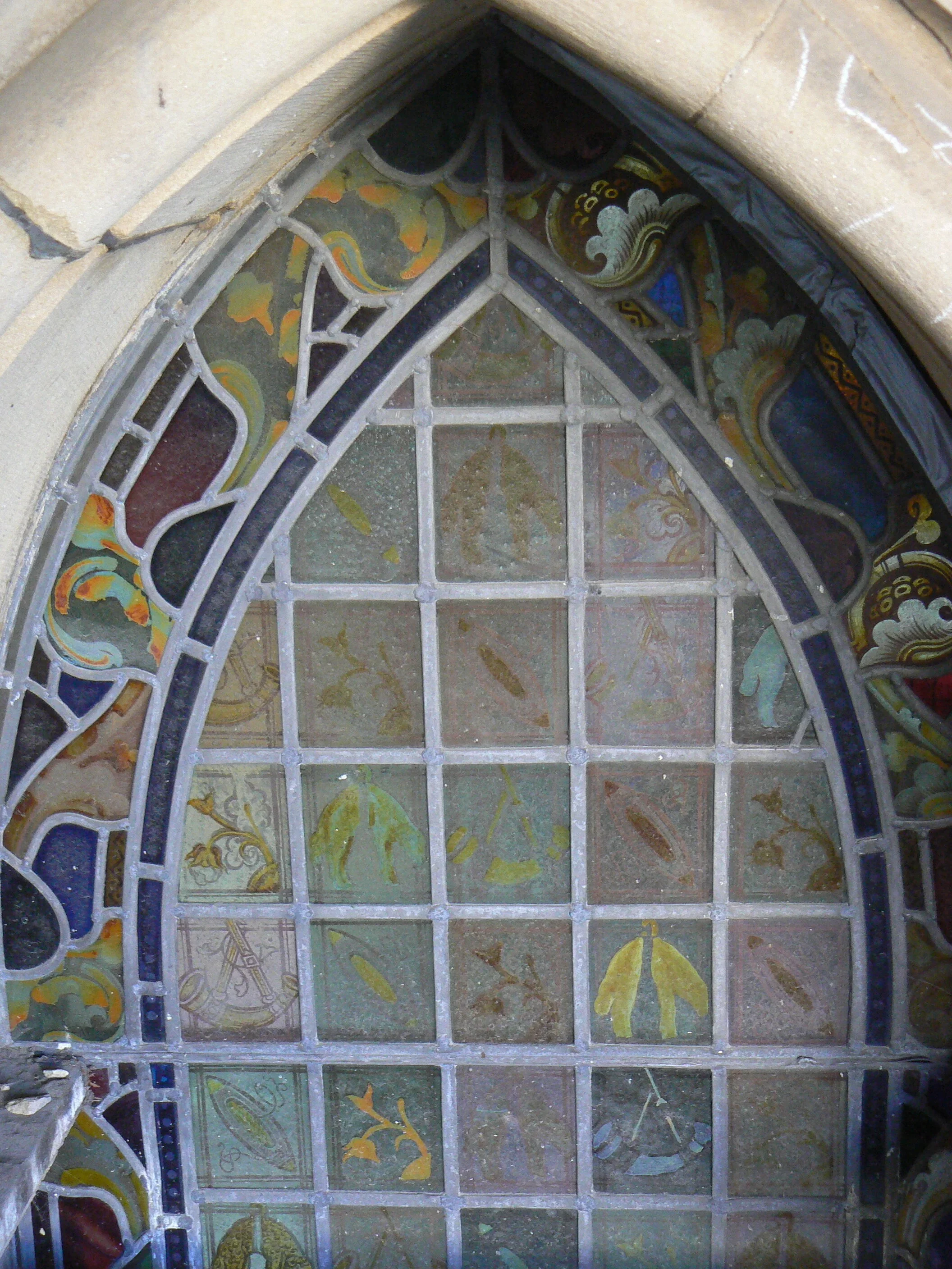 Close-up view of a stained glass window with intricate colorful patterns and designs, set within a stone frame.