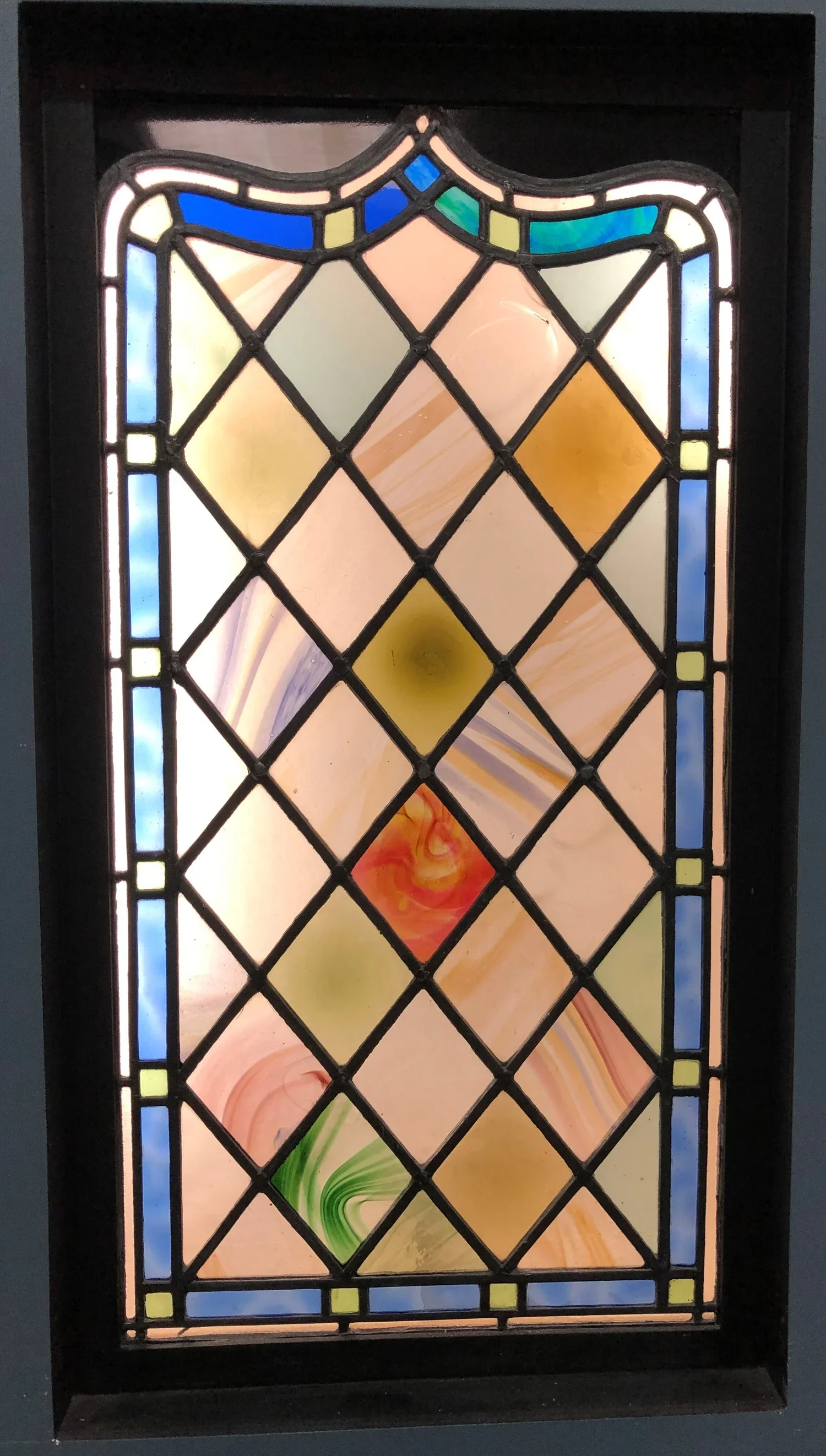Colorful stained glass window with geometric patterns and a black frame.