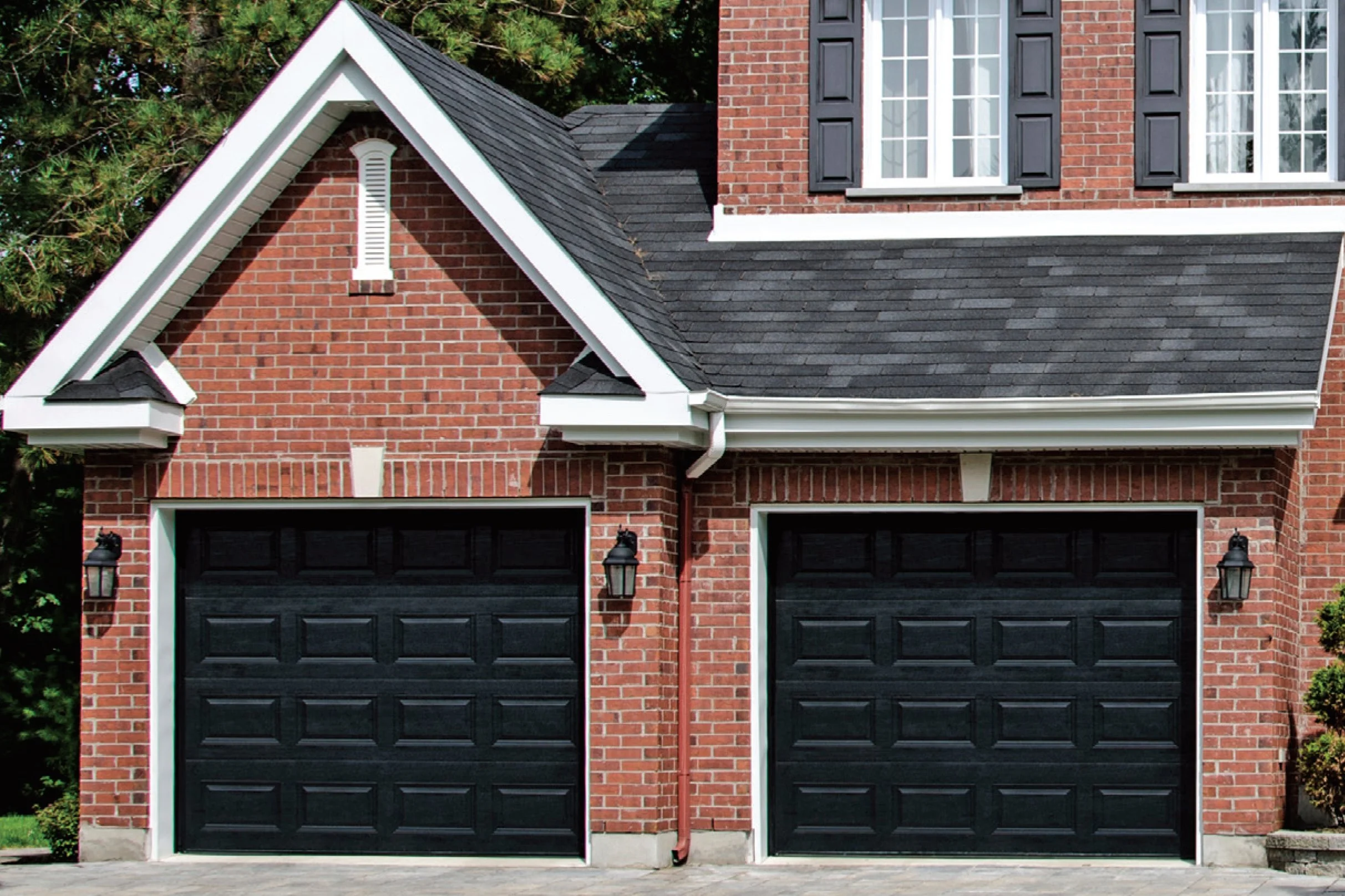 Two Black Steel Traditional Raised Panel Garage Door on Brick House