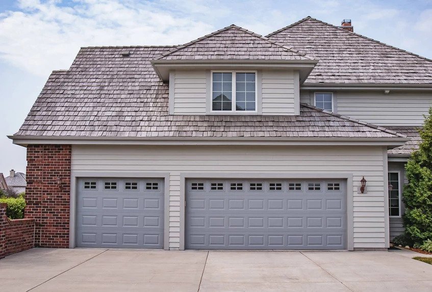Two Gray Steel Traditional Raised Panel Garage Doors on Brown House