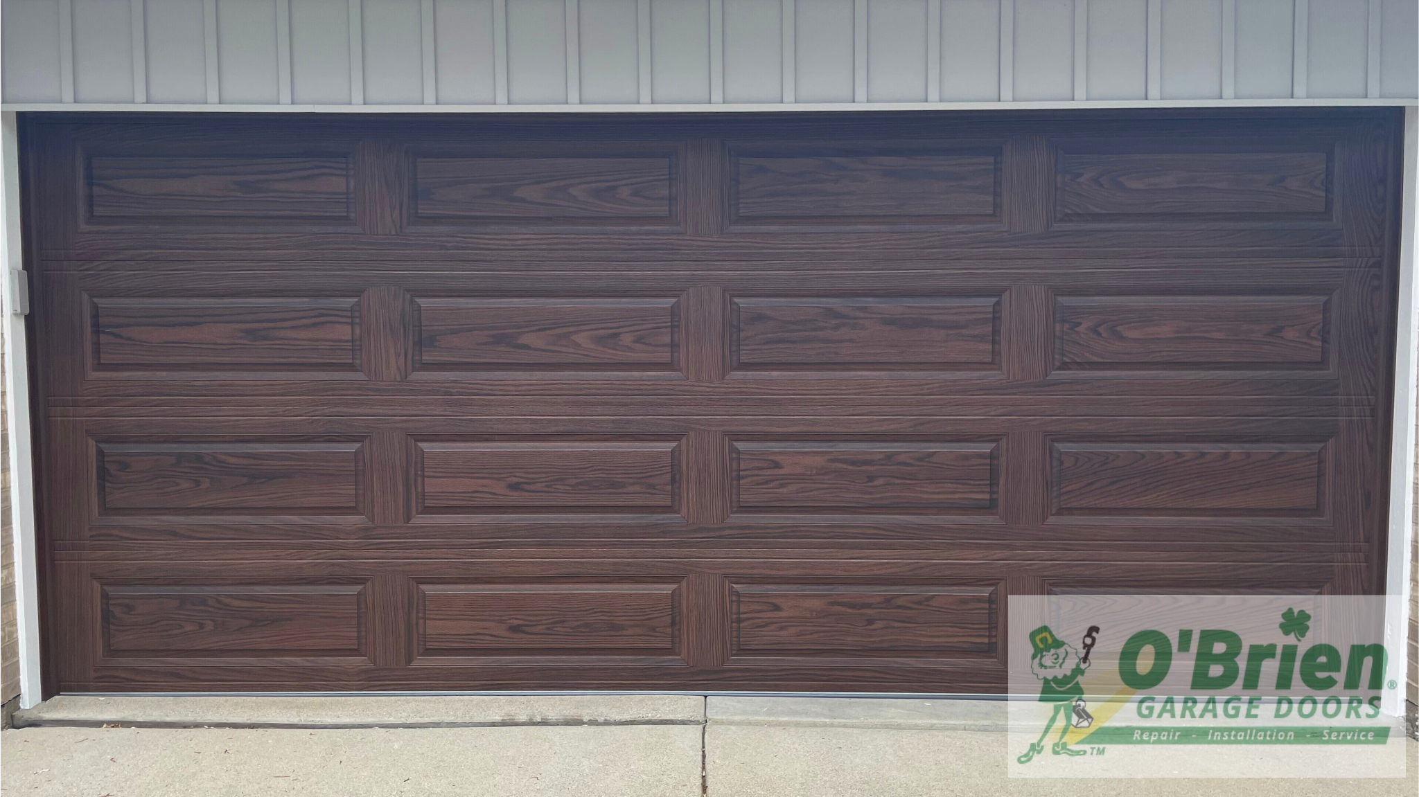 Long Raised Panel Garage Door Steel Back Insulated in Accent Wood Tone Dark Oak no Windows Font View