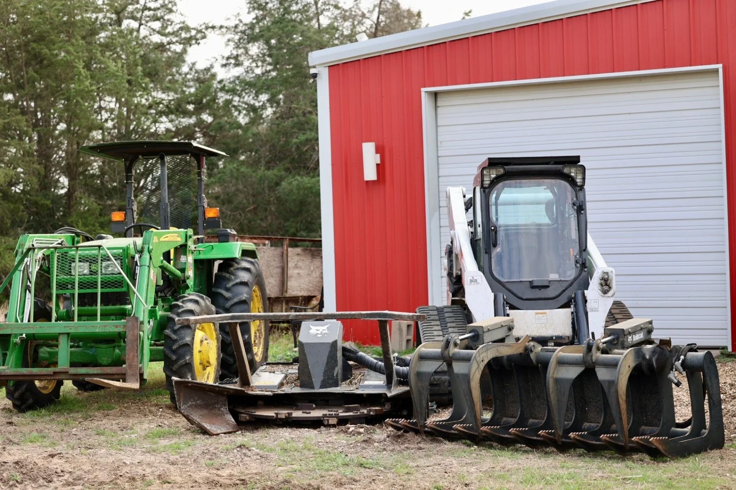 Woodchuck tractor, Bobcat, mulcher, and grapple equipment lineup