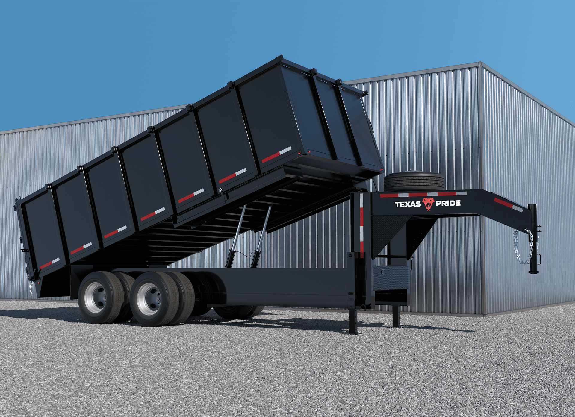 A black dump trailer with hydraulic lift system in front of a metallic building with vertical siding under a clear blue sky.