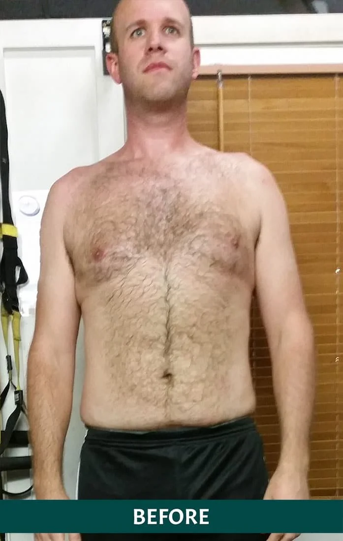 A shirtless man with a muscular build and chest hair standing indoors with a neutral expression.