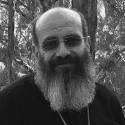 Silhouette of a person's head and shoulders against a black background, backlit with white and red lighting outlining the edges.