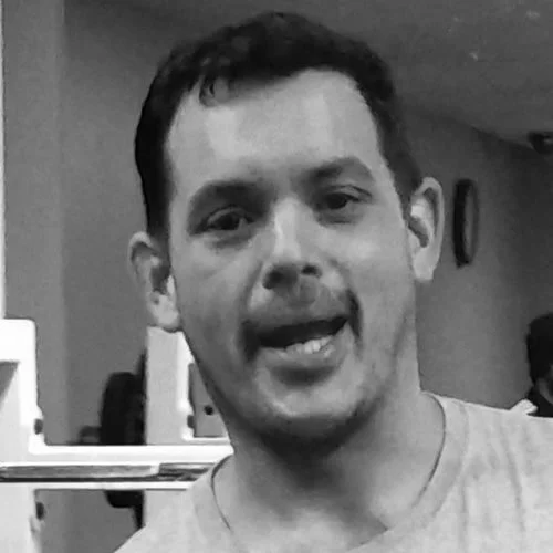 Silhouette of a person with backlit hair and ears, facing away in a dark setting.