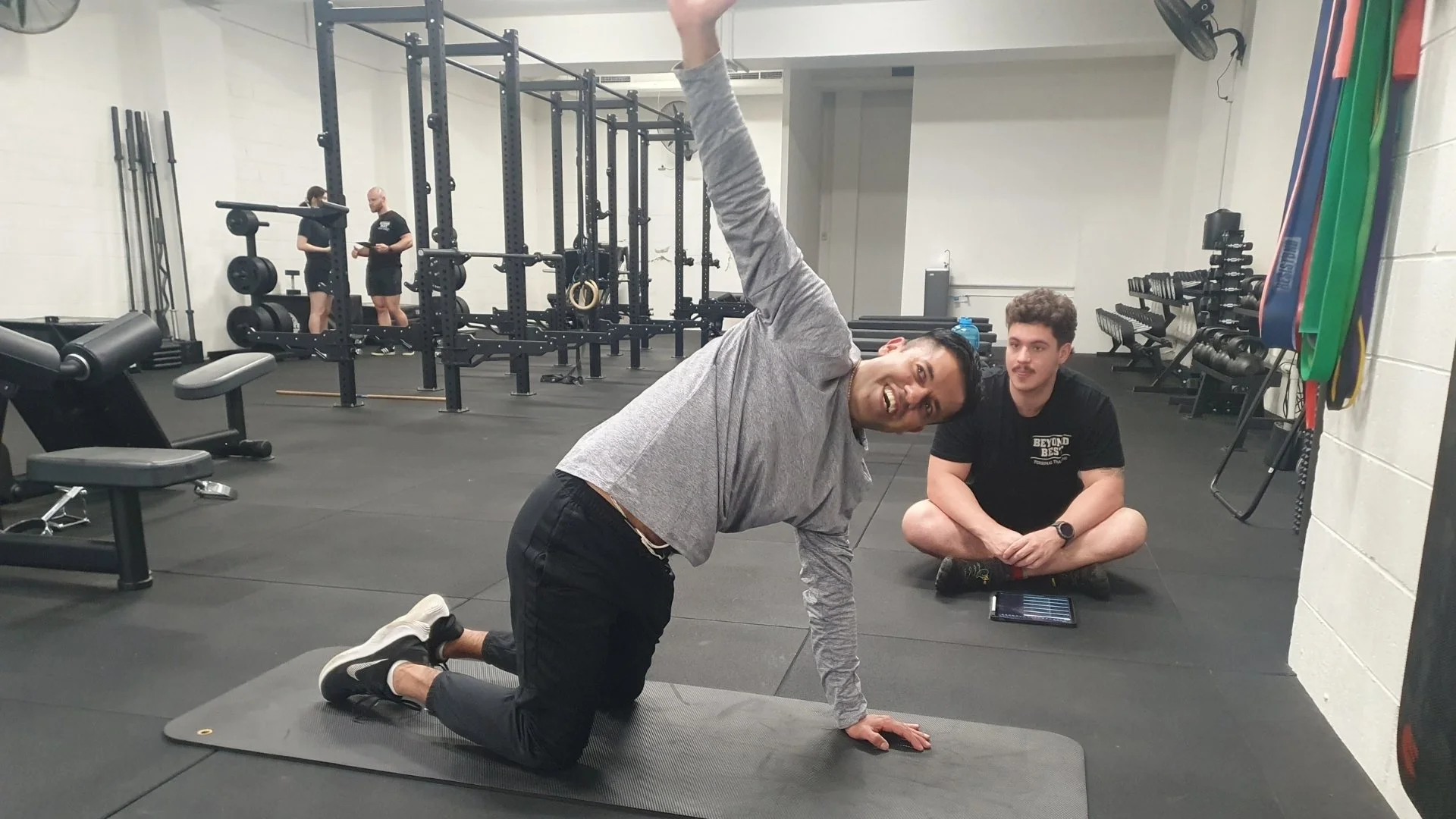 Client completing a mobility exercise on a mat with a Beyond Best coach guiding him in the Collingwood studio.