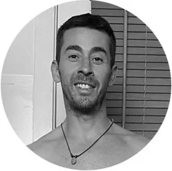 Silhouette of a person's head and shoulders with backlighting, creating a glow around the hair and edges of the face, on a entirely black background.