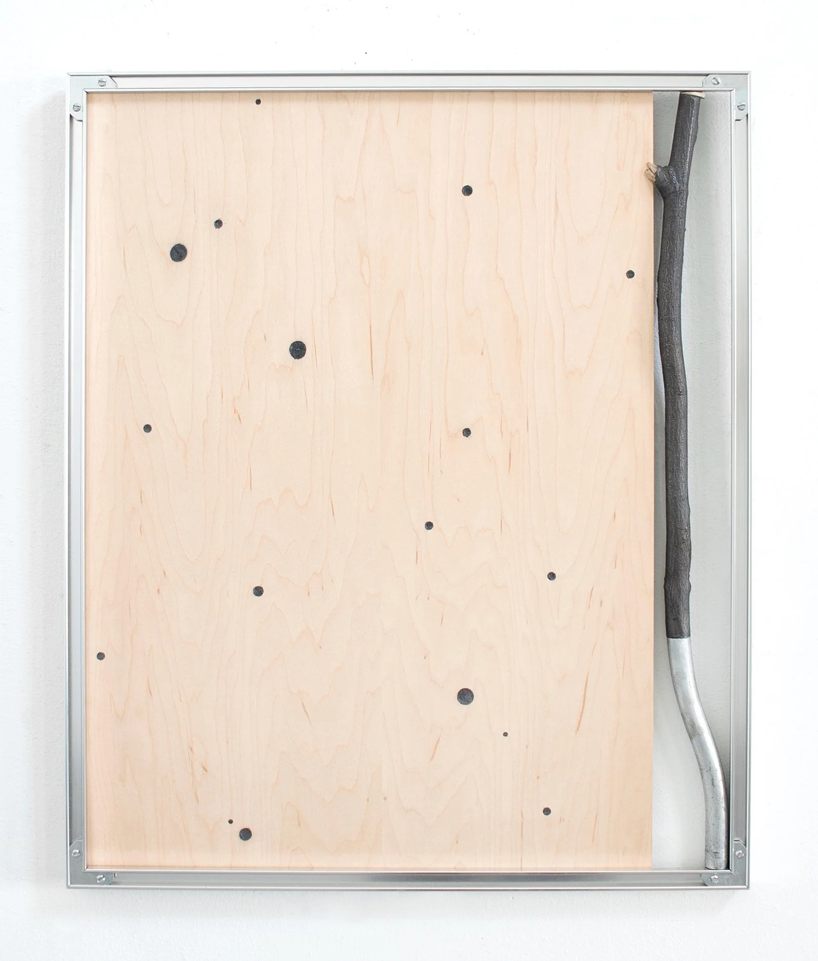 A metal framed wall with a light wooden panel mounted on it, featuring black circular spots and a black branch attached to the right side.
