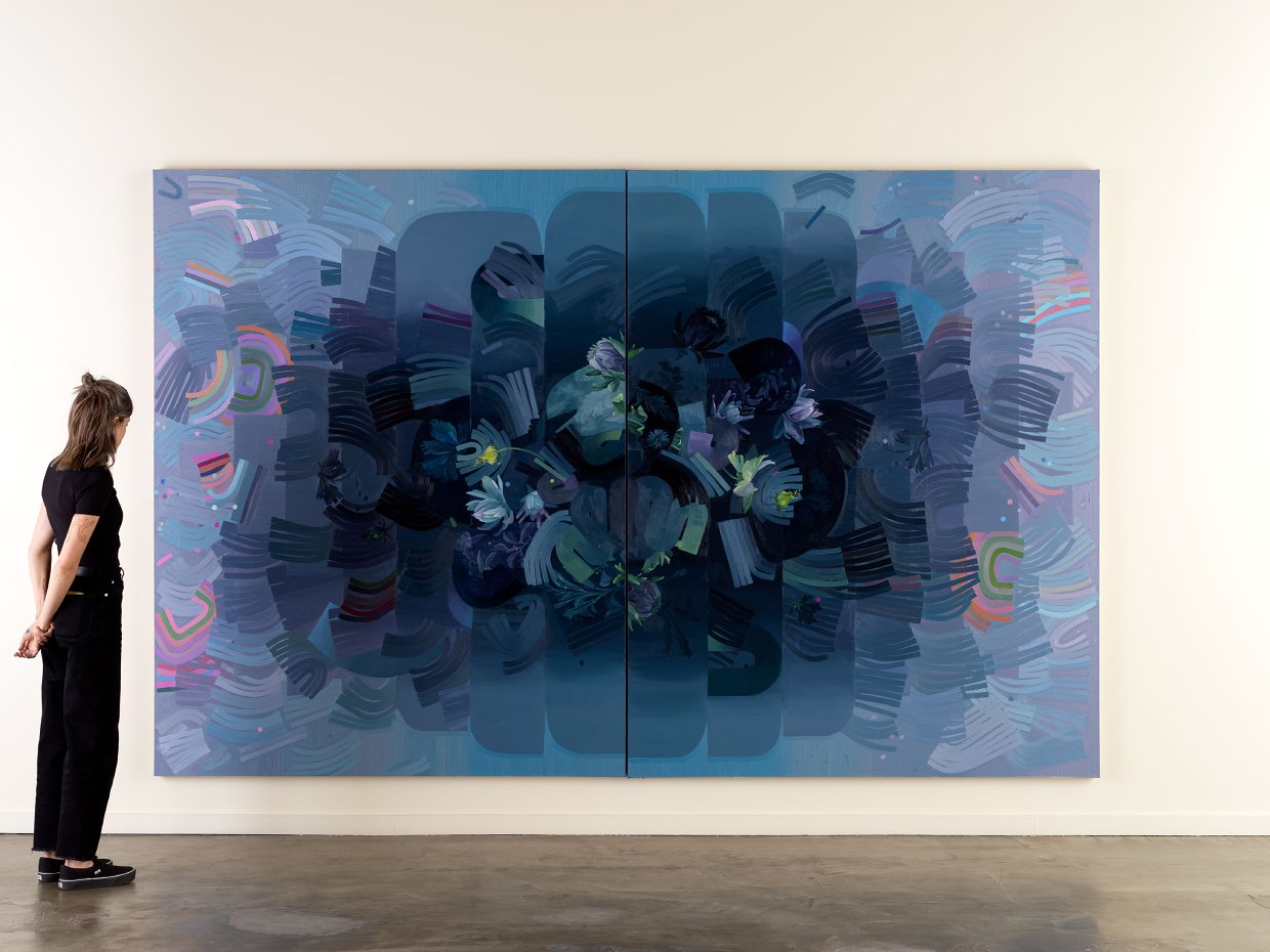 A woman stands in front of a large abstract painting with various shades of blue, purple, and green, featuring swirling patterns and floral elements.