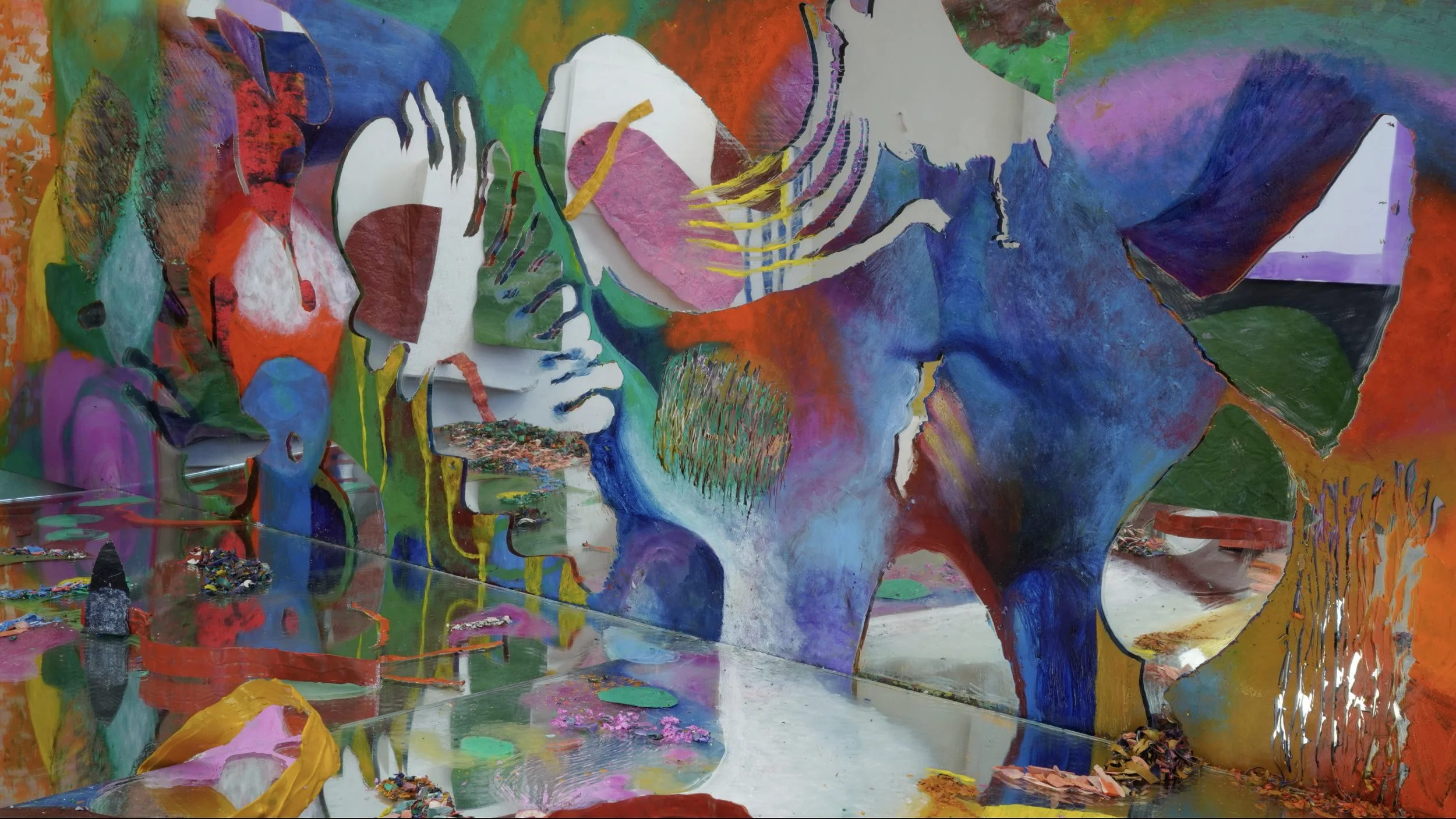 A colorful abstract mural featuring various shapes, lines, and textures in bright colors, including pink, blue, green, yellow, orange, and purple.