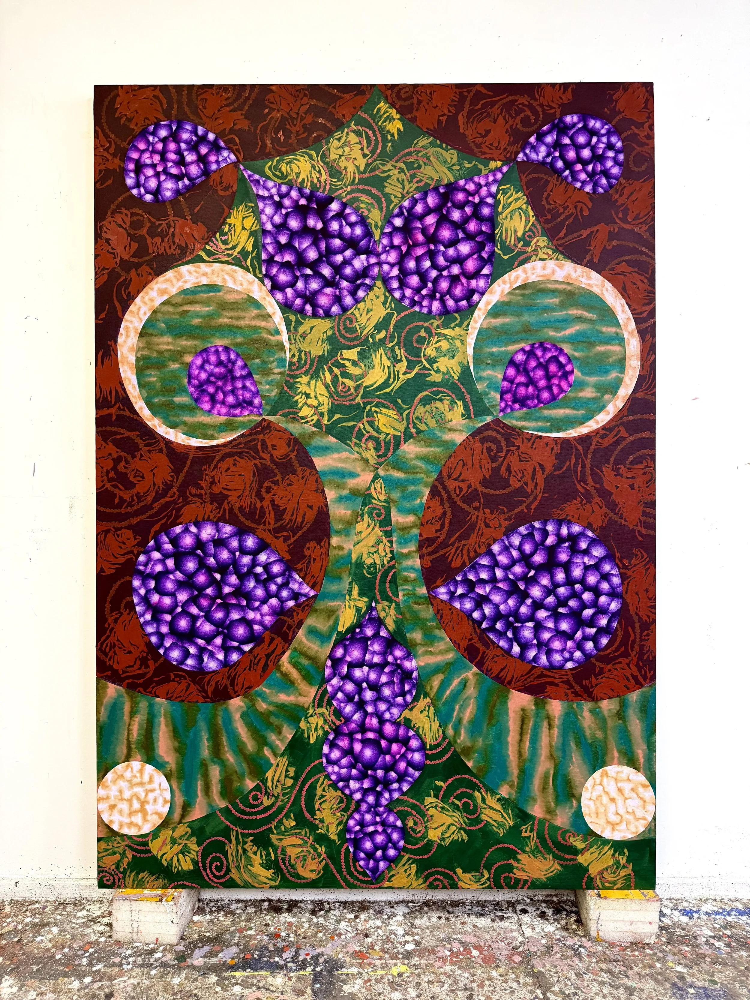 Abstract painting with purple, green, and orange swirls and geometric shapes on a canvas, supported by two bricks, placed on a colorful splattered floor.