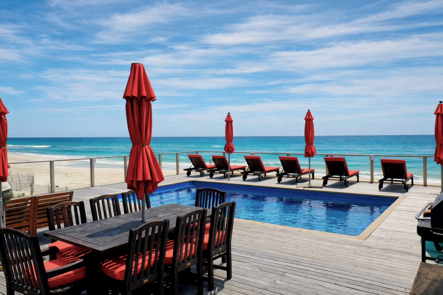 Fir Island Pines ocean front pool deck with red umbrellas and lounge chairs