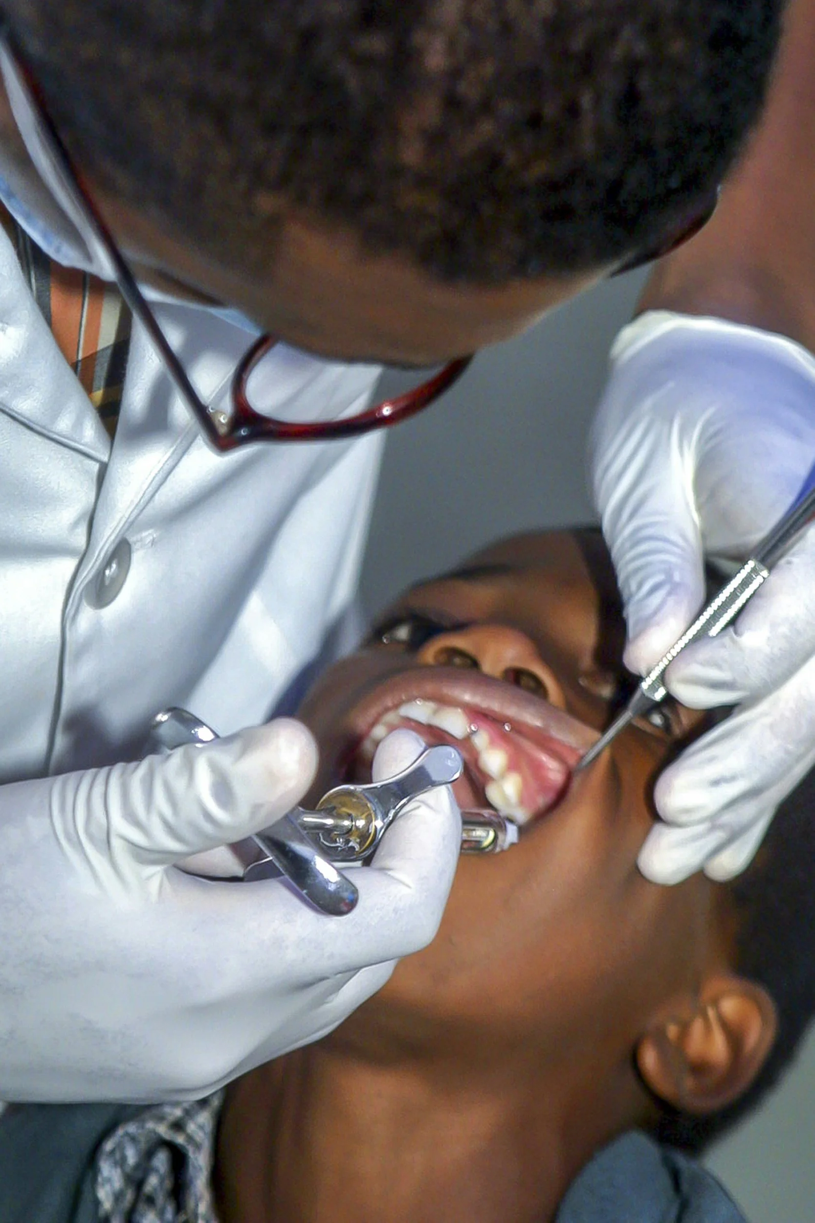 A dentist examines a patient's teeth using dental tools in a dental clinic.