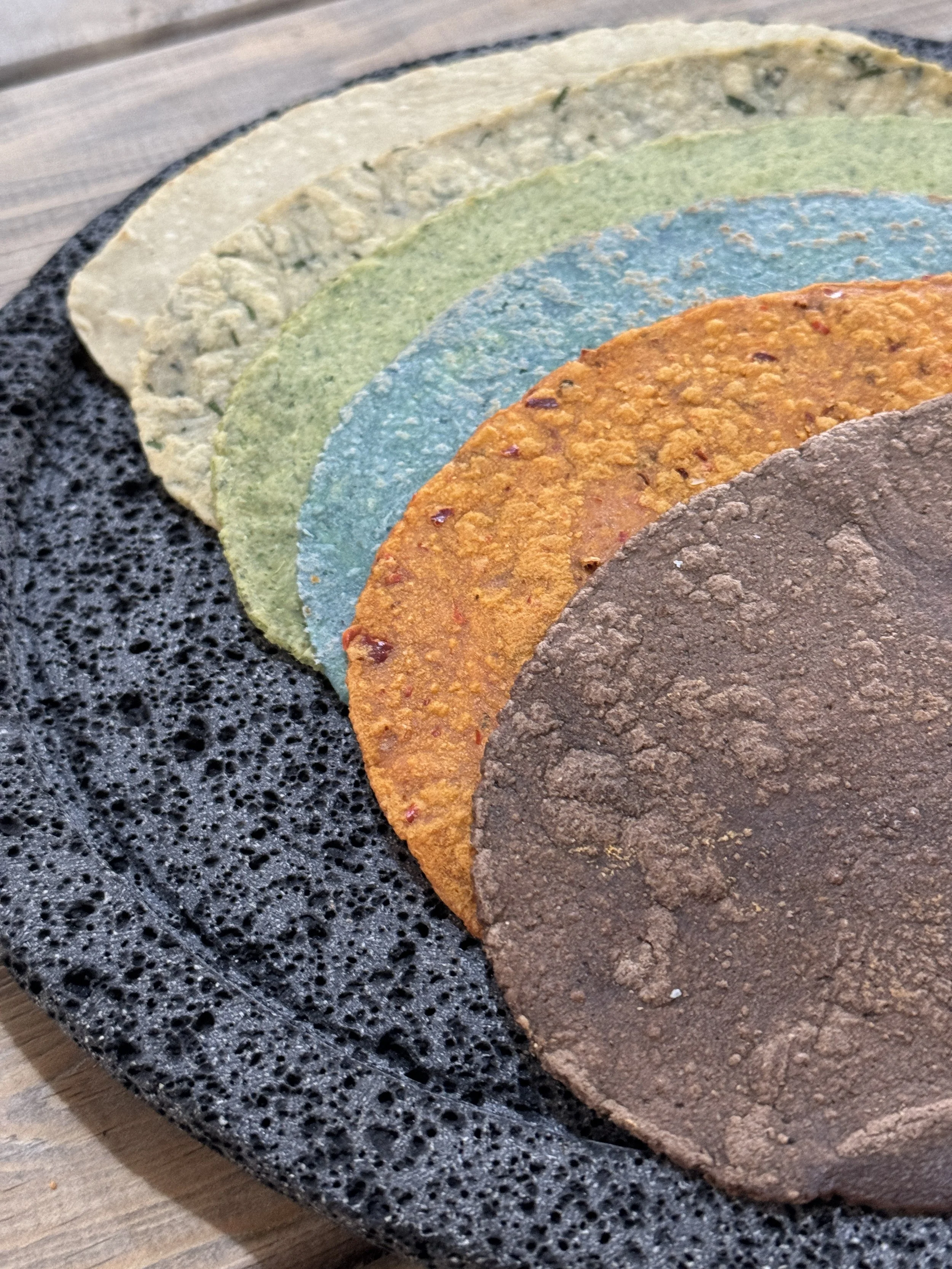 Laminas de maíz de diferentes colores y sabores en una fuente negra de piedra