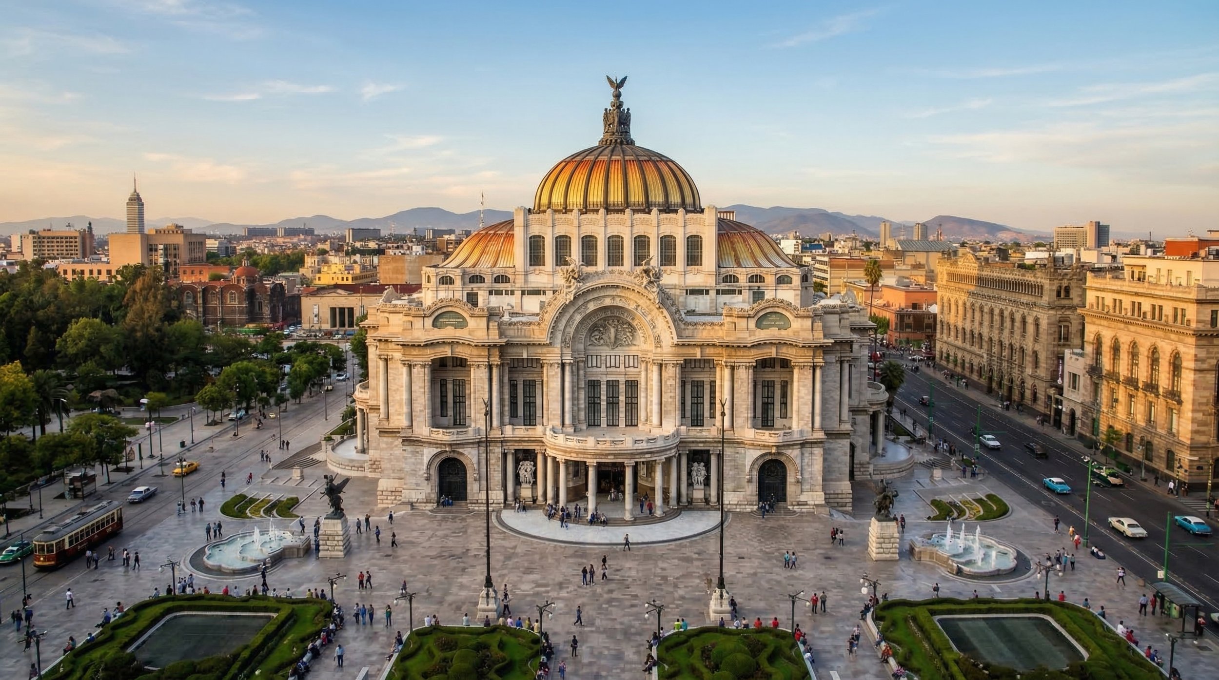 Vista aérea de un edificio grande y antiguo en una ciudad, con una cúpula dorada y detalles arquitectónicos elaborados, en un parque con fuentes y personas caminando.