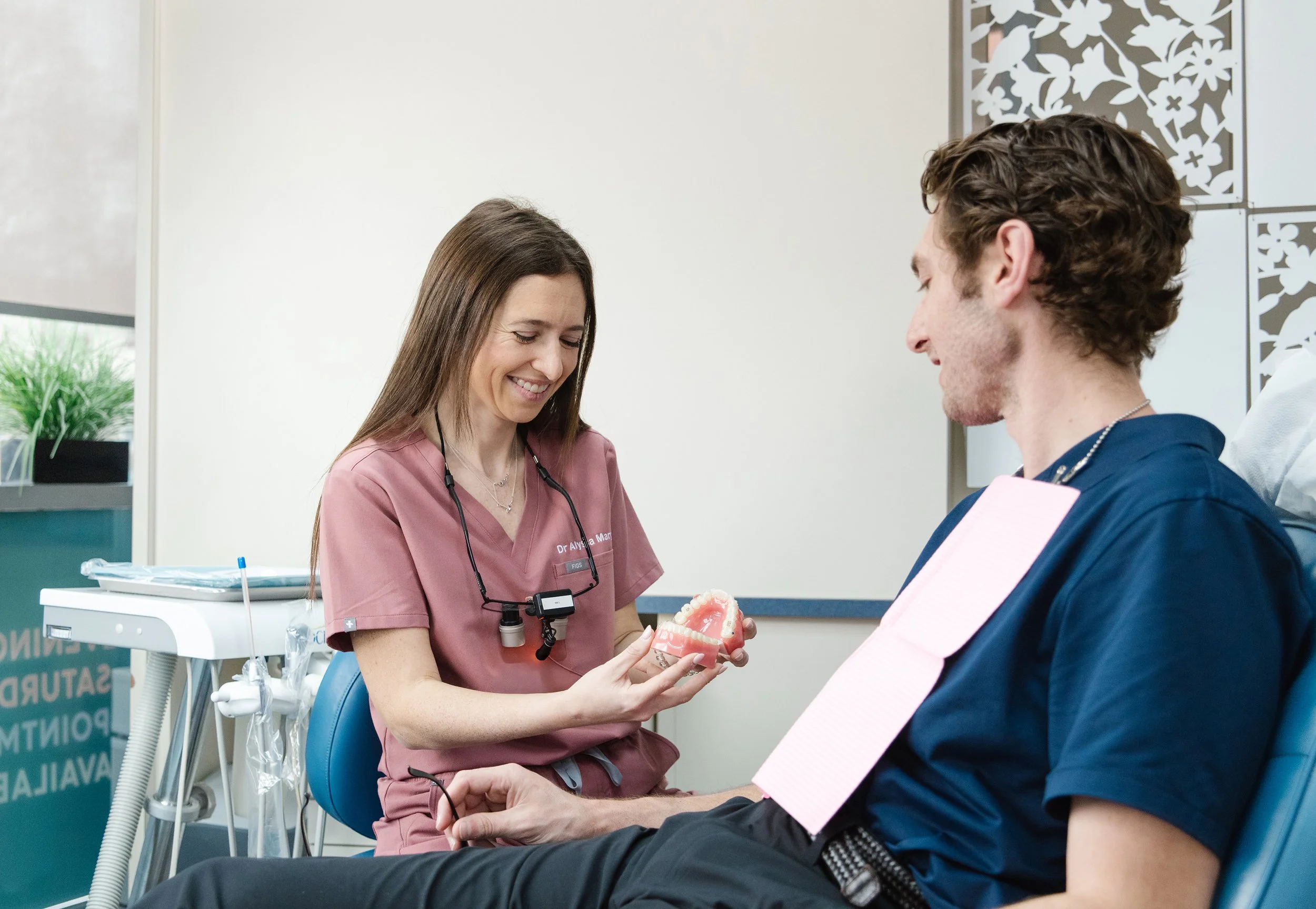 A healthcare professional showing a dental model to a patient in a clinic setting.