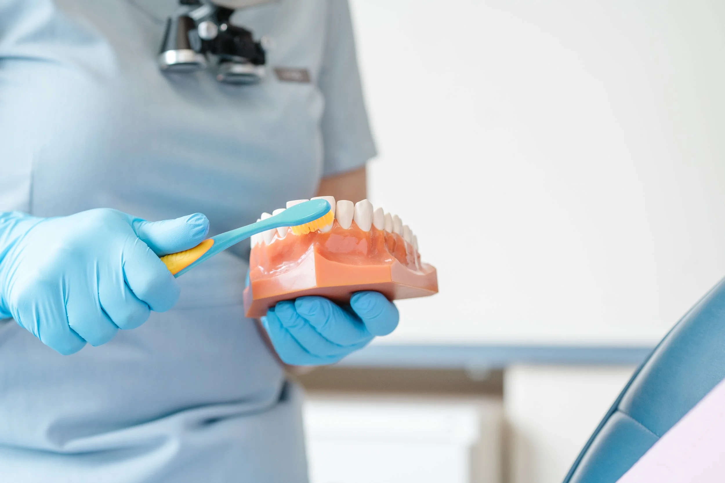 Dental hygienist teaching a patient correct brushing technique during a preventive dental visit in a modern clinic