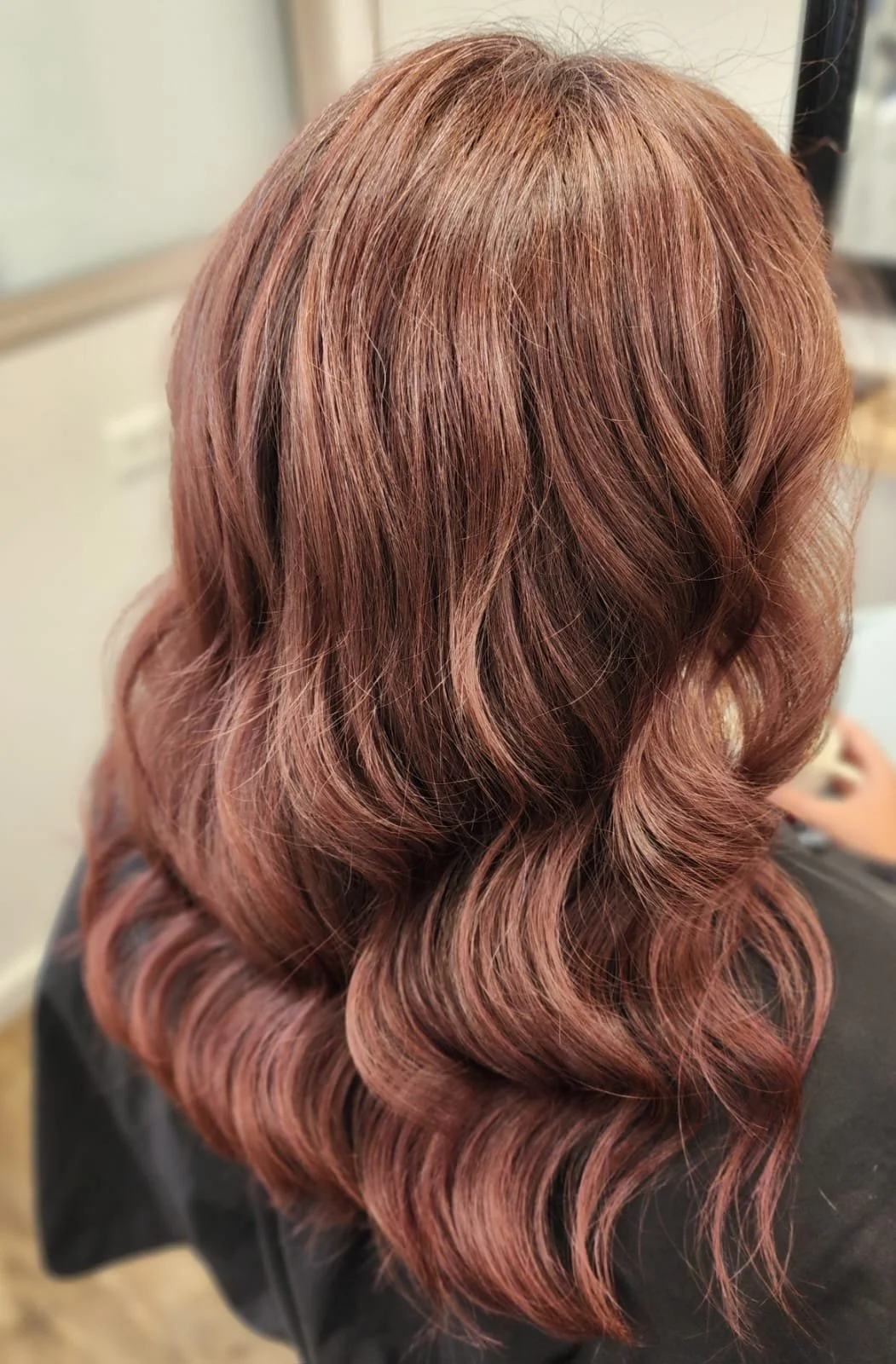 A person with medium-length, styled wavy hair colored in shades of reddish brown.