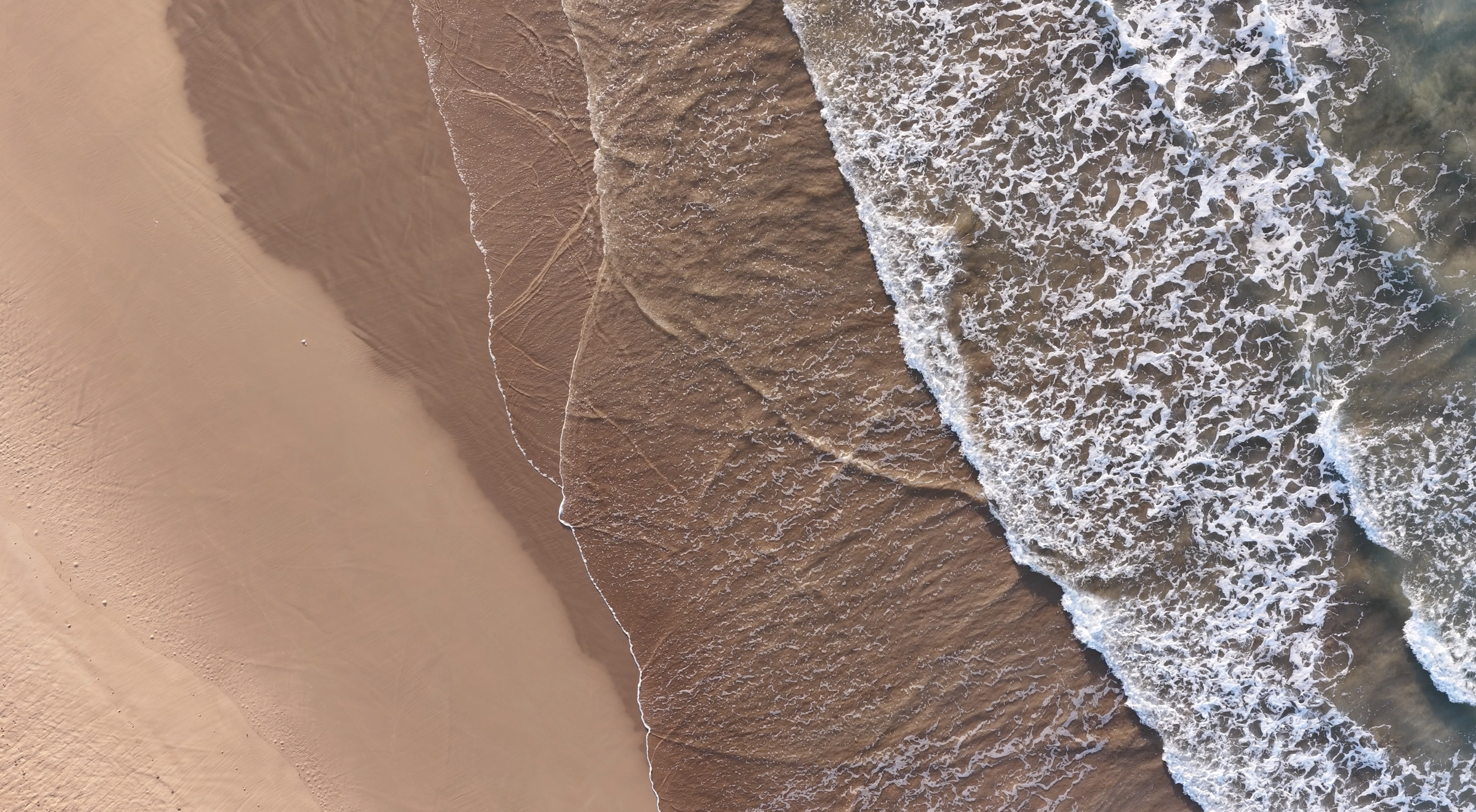 Top-down drone shot of waves meeting shoreline filmed by professional drone operator in Australia
