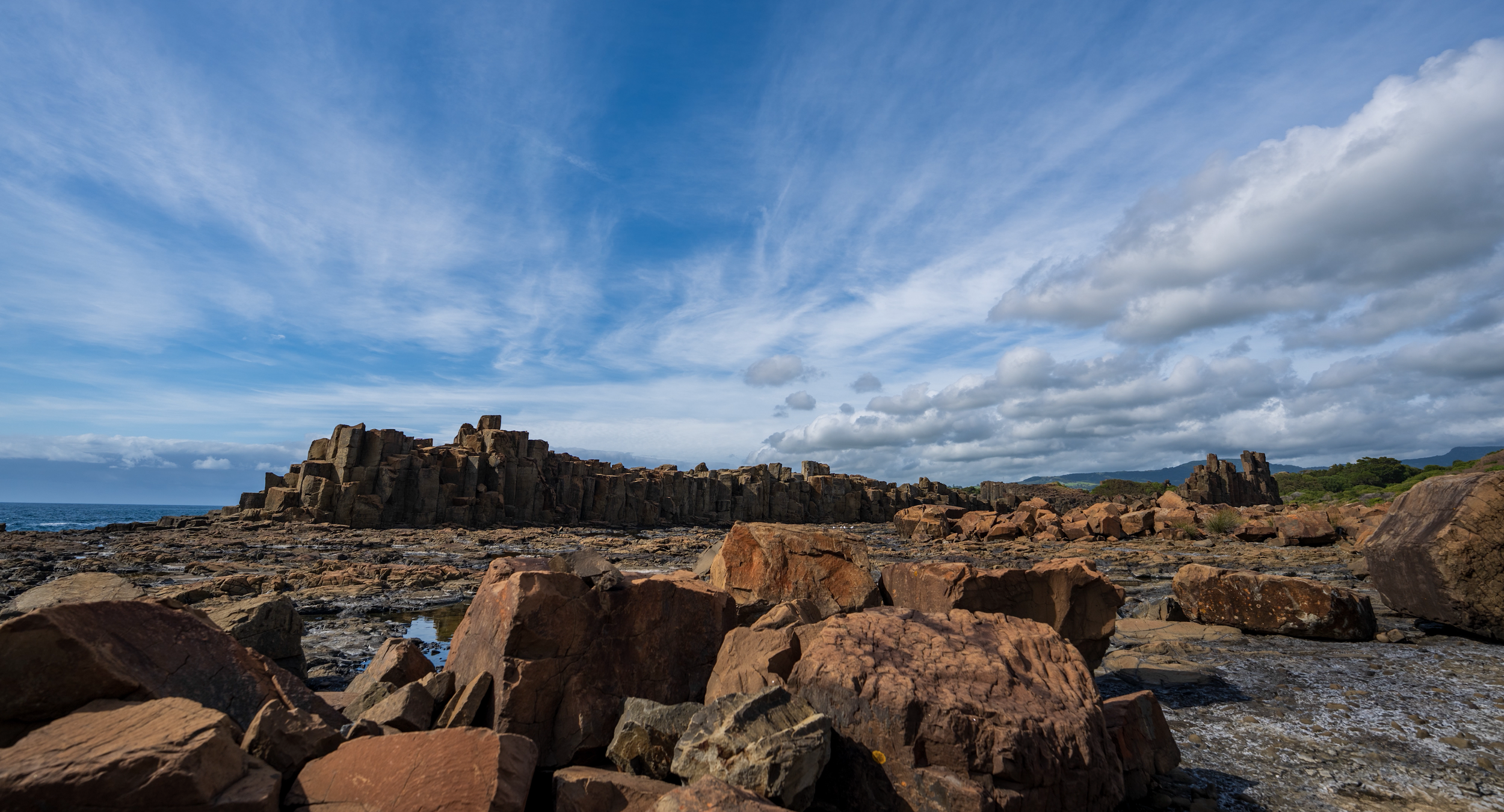 Wide cinematic shot of coastal rock formations under dramatic sky filmed for tourism and documentary production
