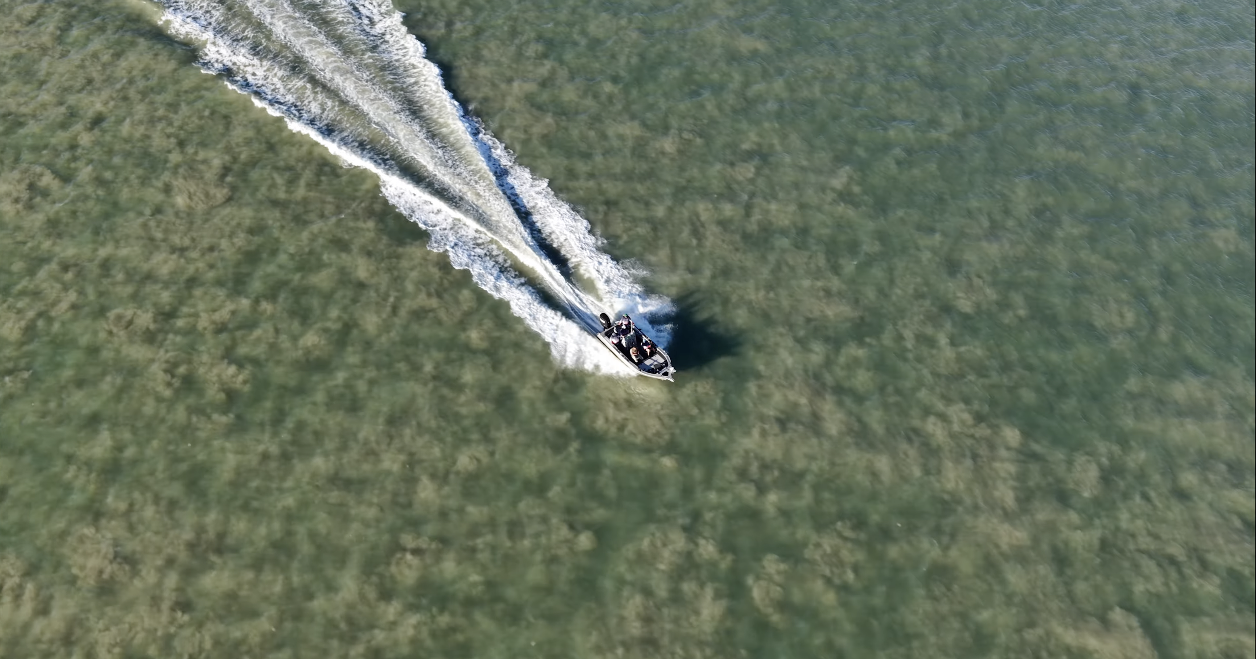 Top-down drone shot of a fishing boat moving through shallow turquoise waters in Darwin’s remote coastal waterways.
