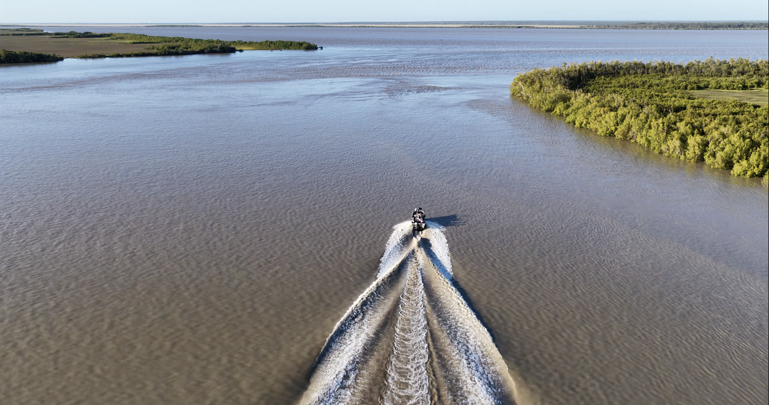 Aerial drone shot of a fishing boat speeding through the vast river systems and wetlands near Darwin, Northern Territory.