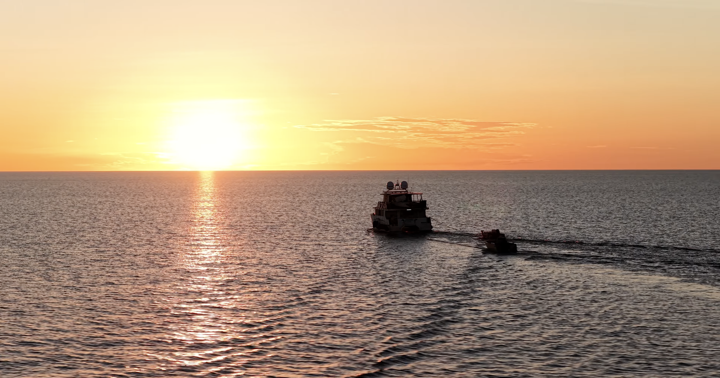 Cinematic drone shot of a vessel crossing open ocean waters at sunset off the coast of Darwin in Northern Australia.