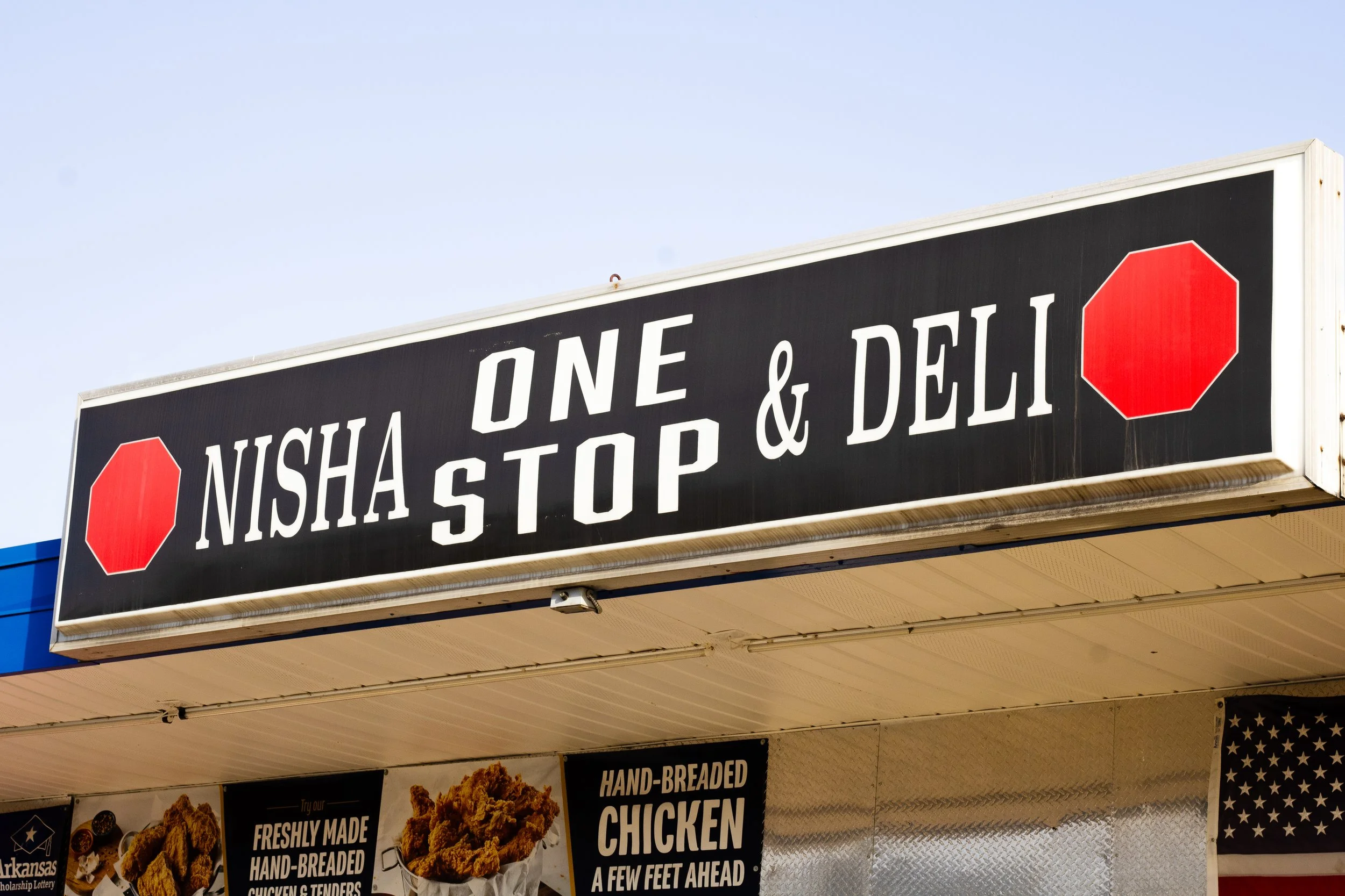 Front of store signage that says "Nisha One Stop + ENJ" located at 900 W Broadway in Morrilton AR. Gas Station, Beer Cave, Minor Groceries with Laundromat Nextdoor.