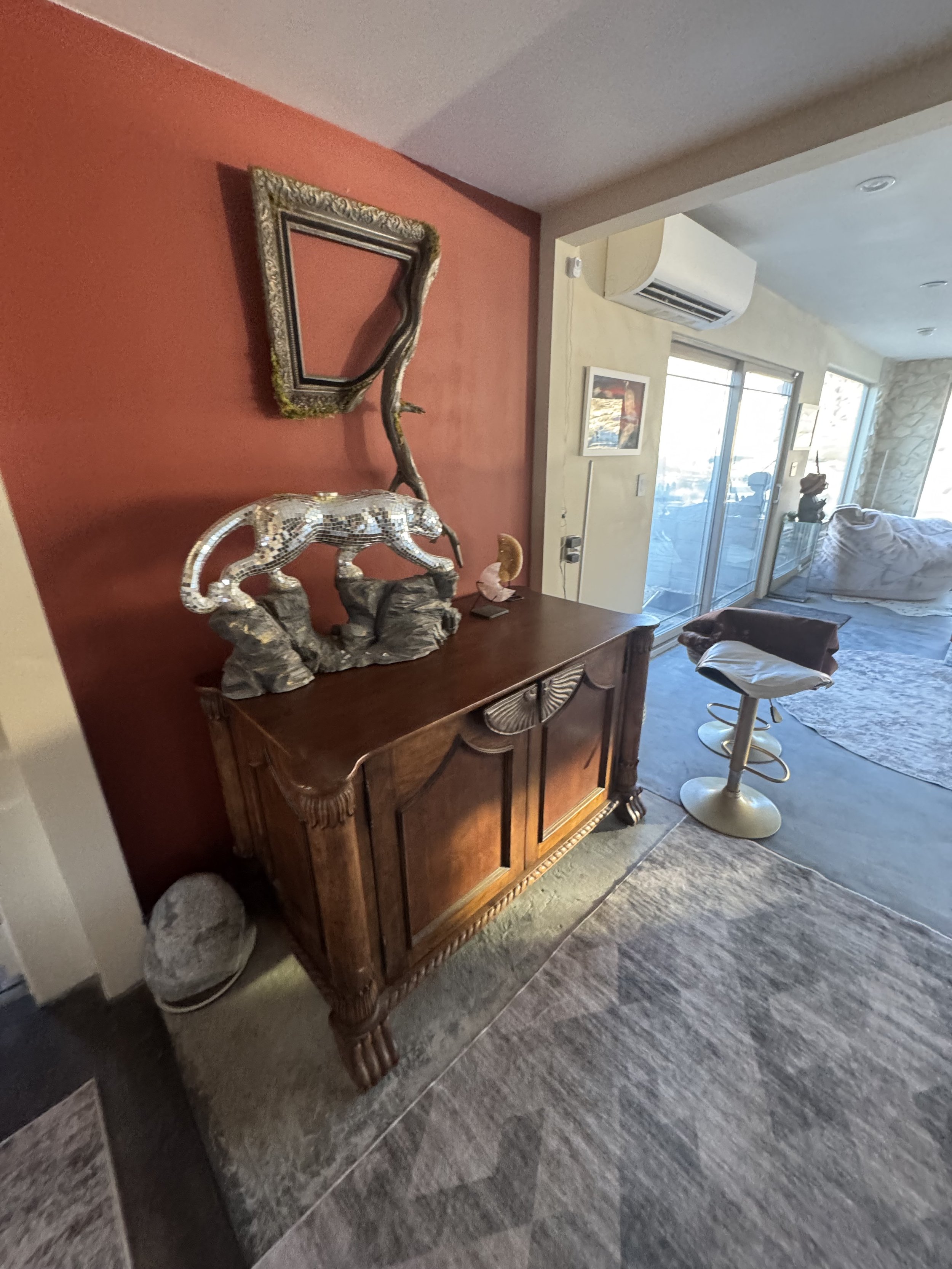 Decorative wooden sideboard with animal figurines and picture frame against red wall in living room.