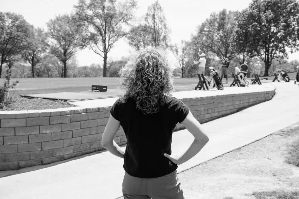 black and white photograph of sport psychologist observing golfers practicing at the range